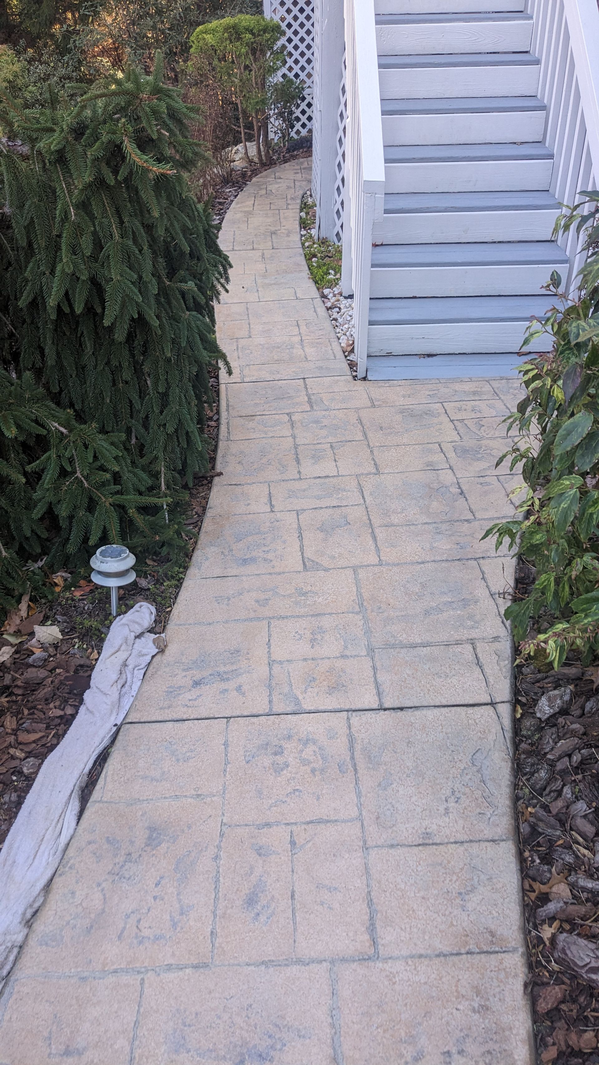 A walkway leading to a house with stairs on the side of it.