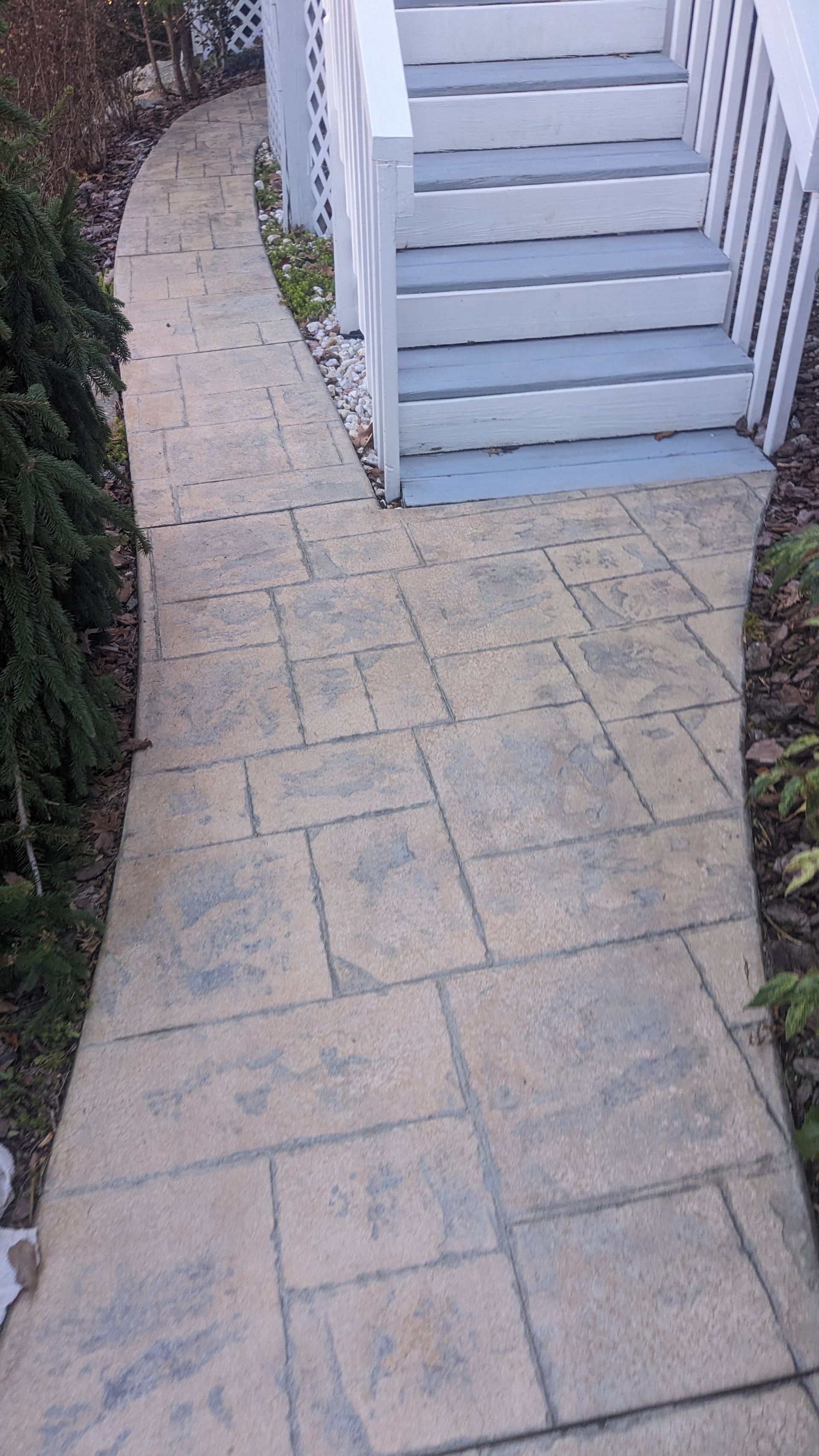 A sidewalk leading to a set of stairs next to a house.