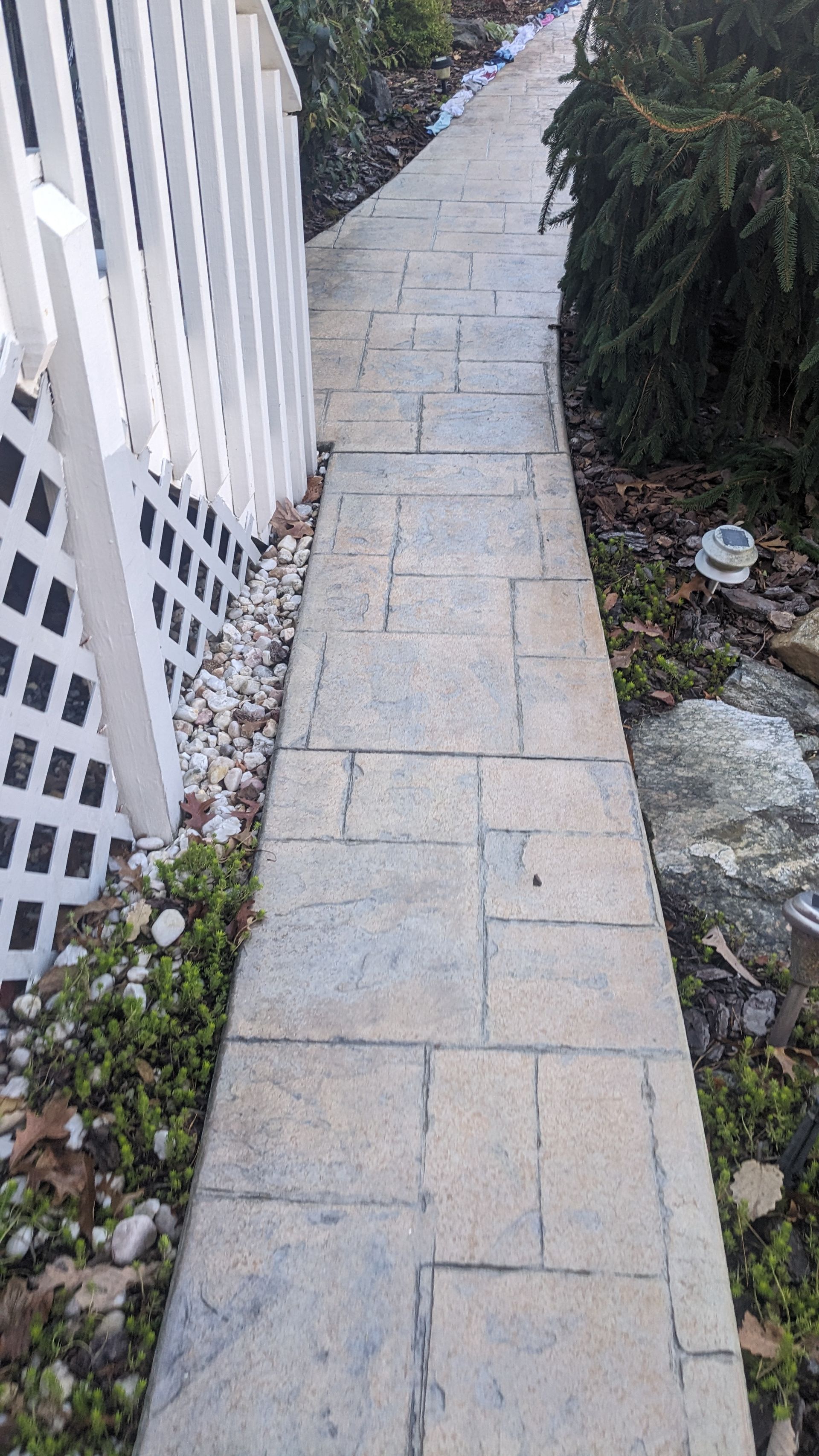 A stone walkway leading to a white fence.