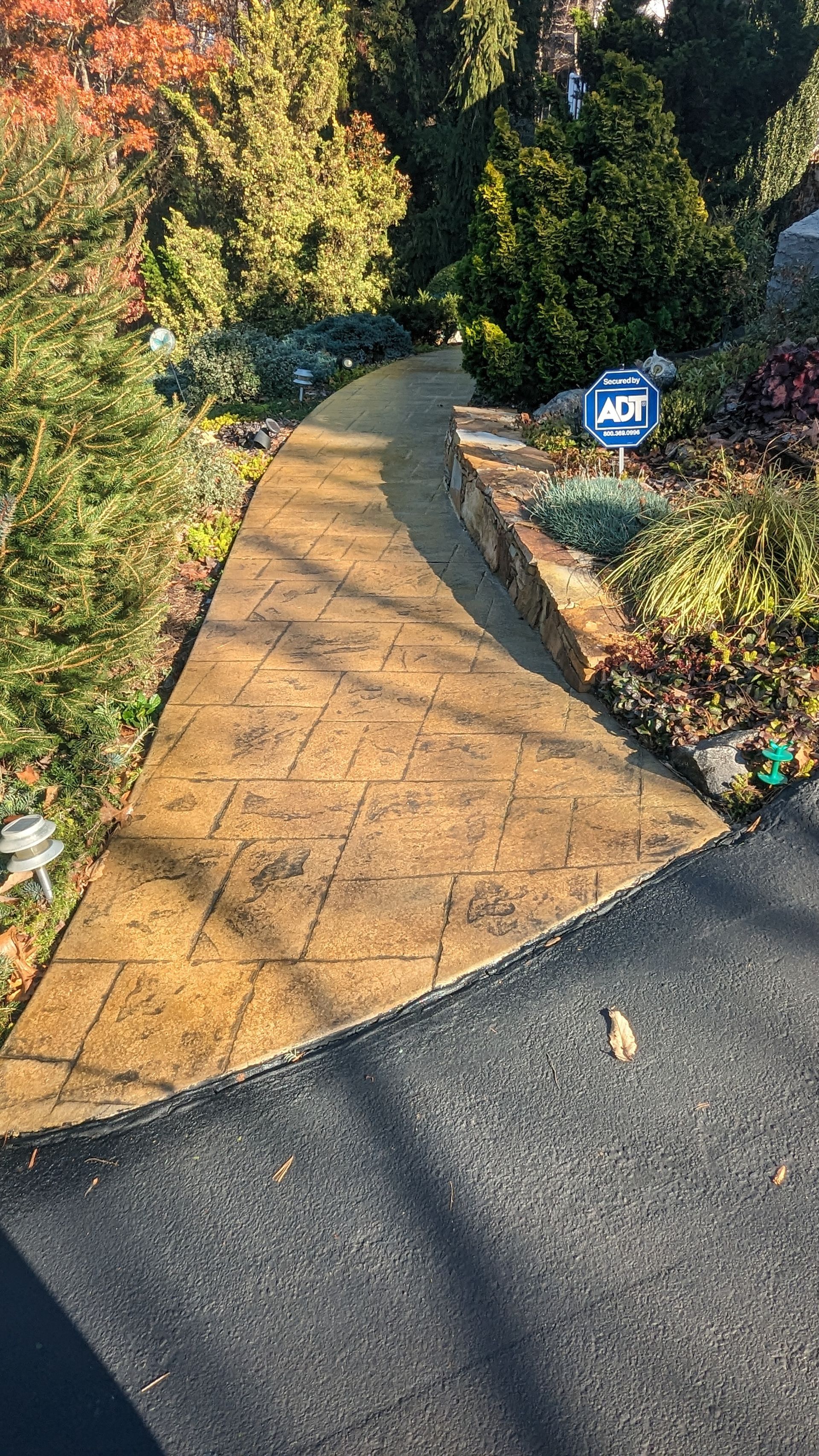 A walkway leading to a garden with a sign on the side of it.