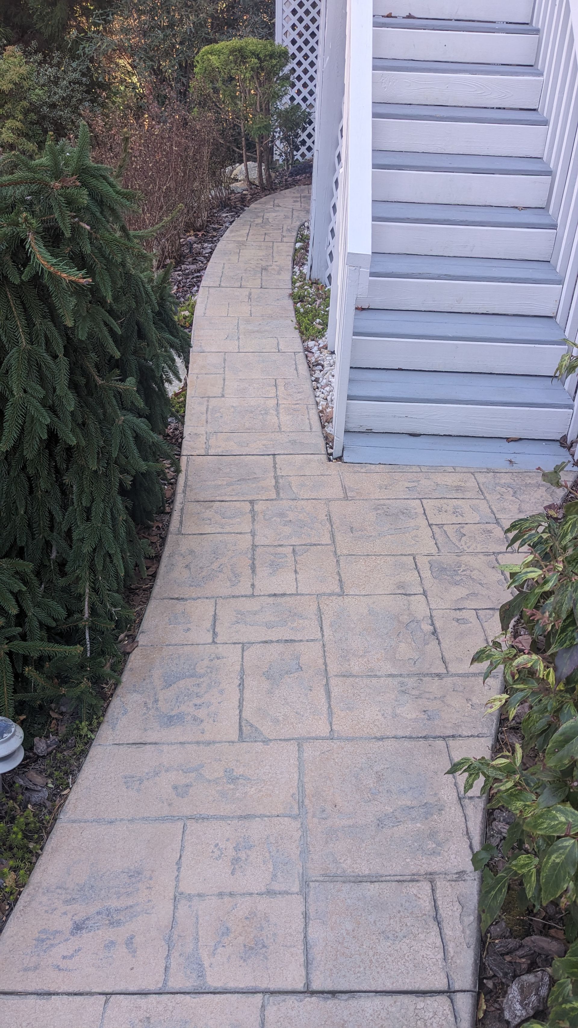 A brick walkway leading to a white building with stairs.