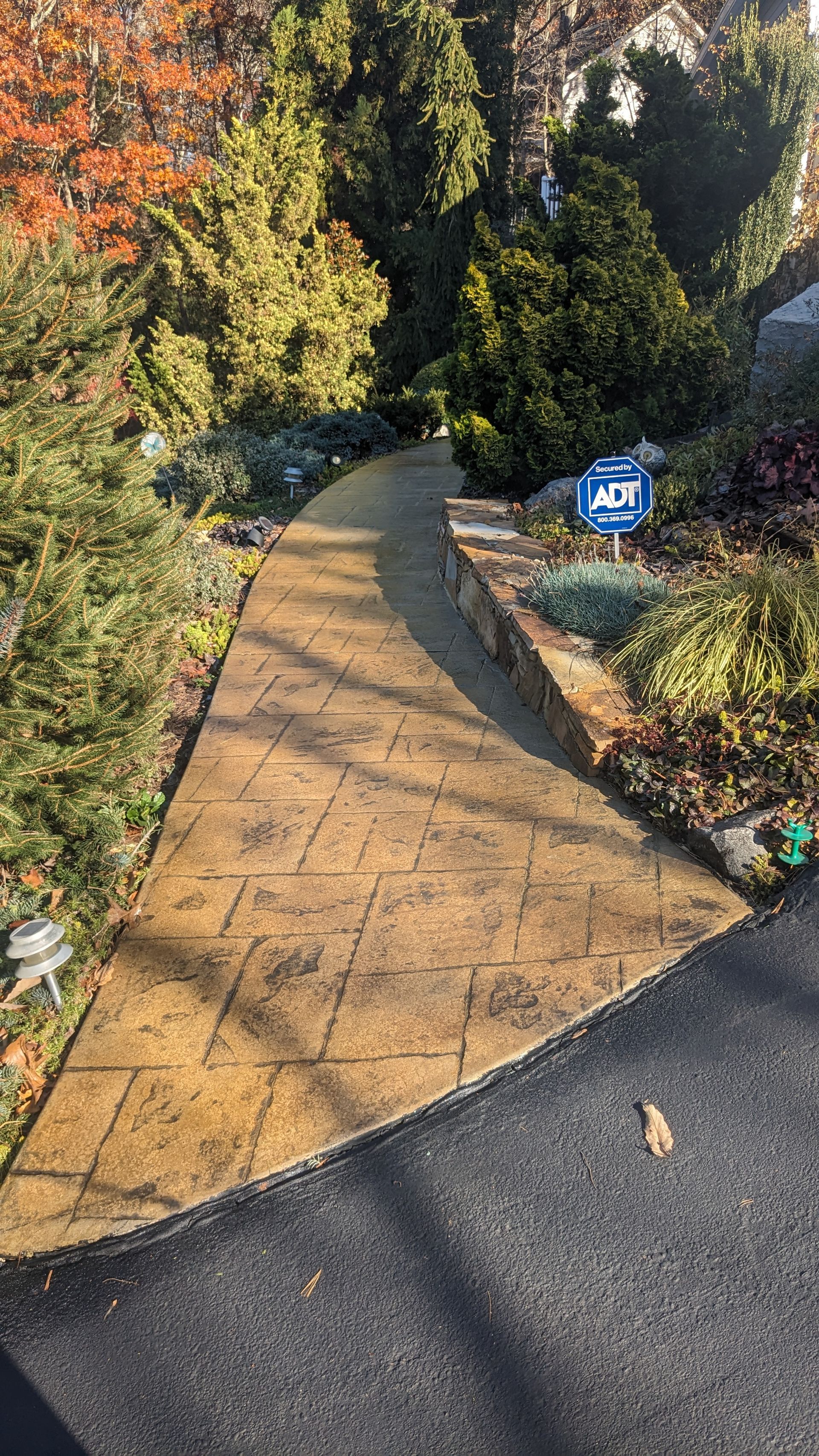 A walkway with a sign on the side of it going through a park.