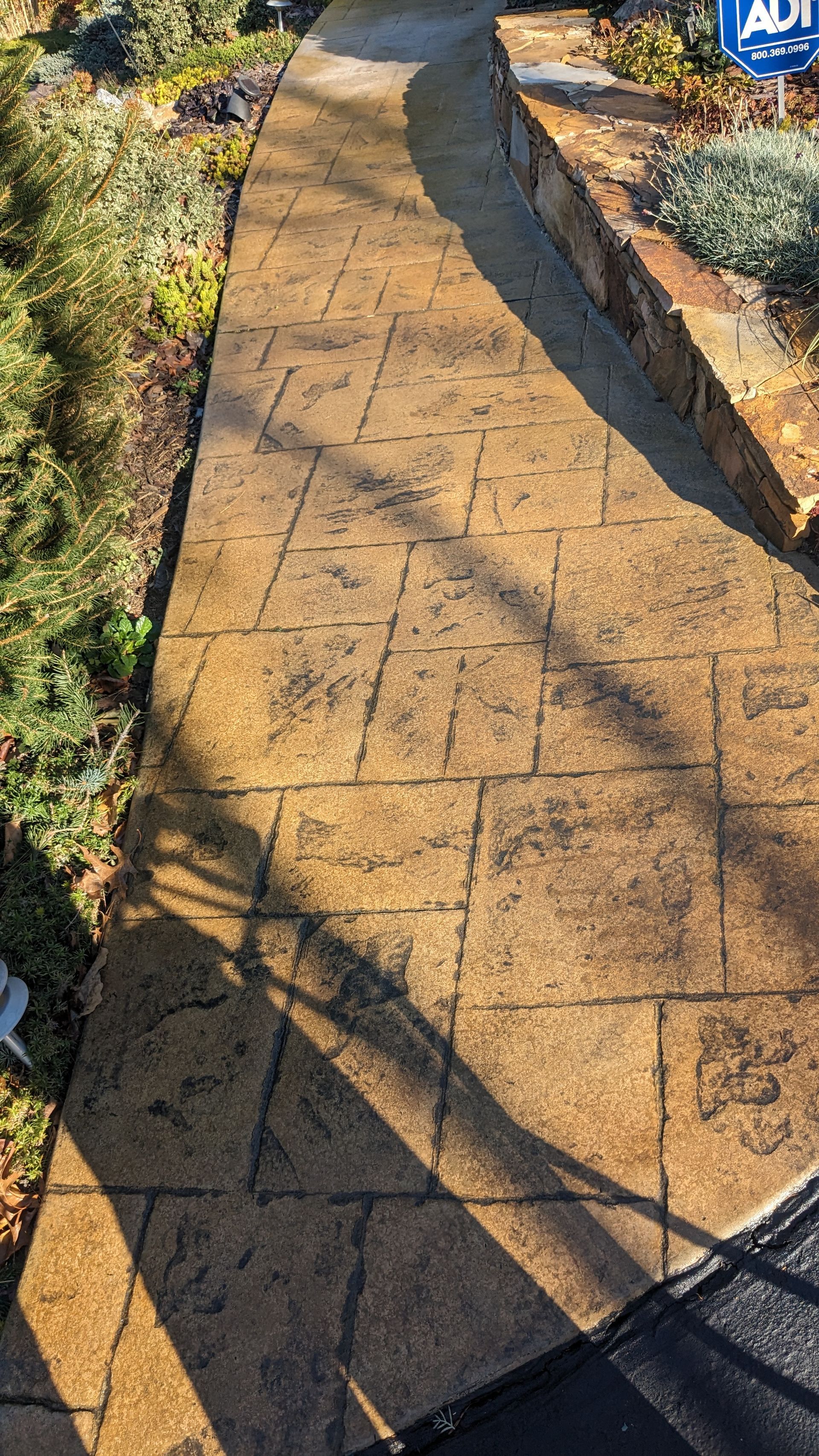 A brick walkway with a sign on the side of it.
