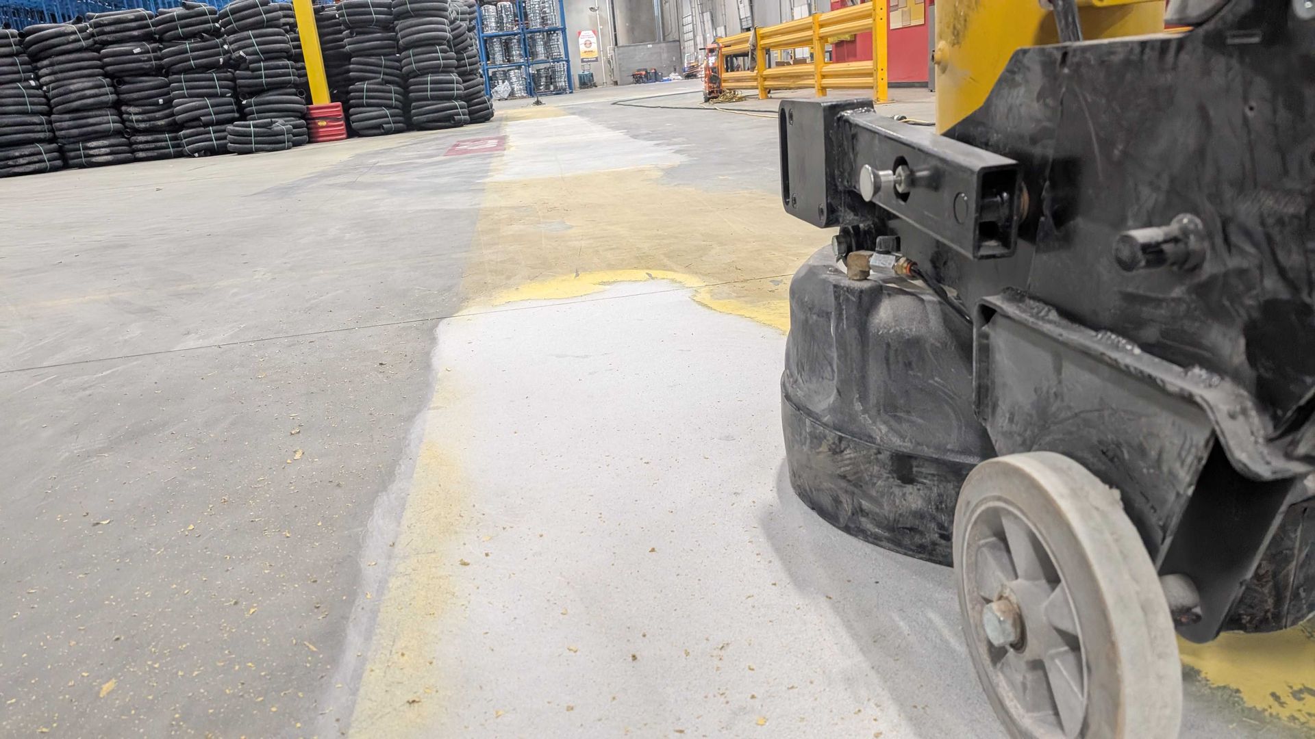 A machine is grinding concrete in a warehouse.