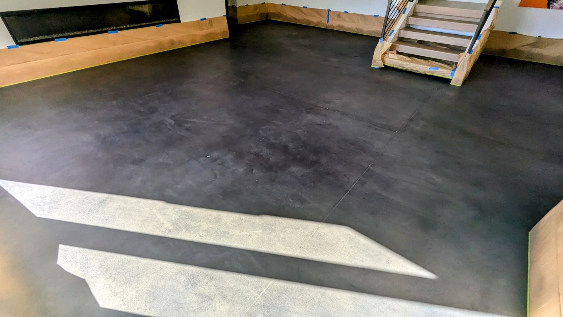 A living room with a black concrete floor and stairs.