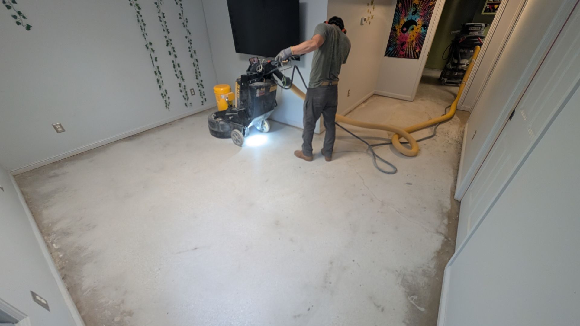 A man is cleaning the floor of a room with a vacuum cleaner.