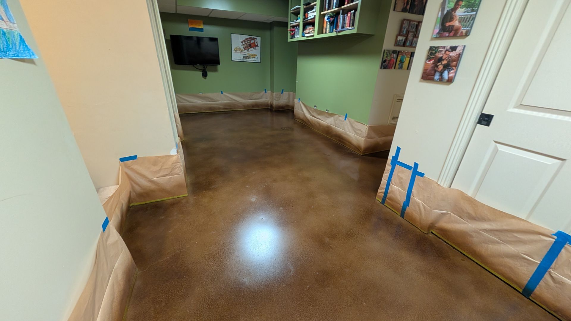 A room with a concrete floor and a tv on the wall.