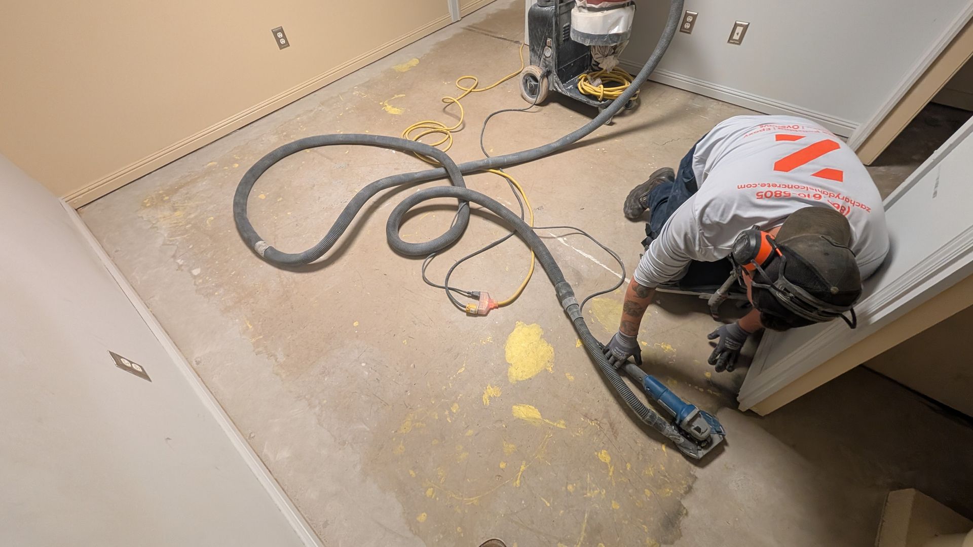 A man is kneeling on the floor using a vacuum cleaner.