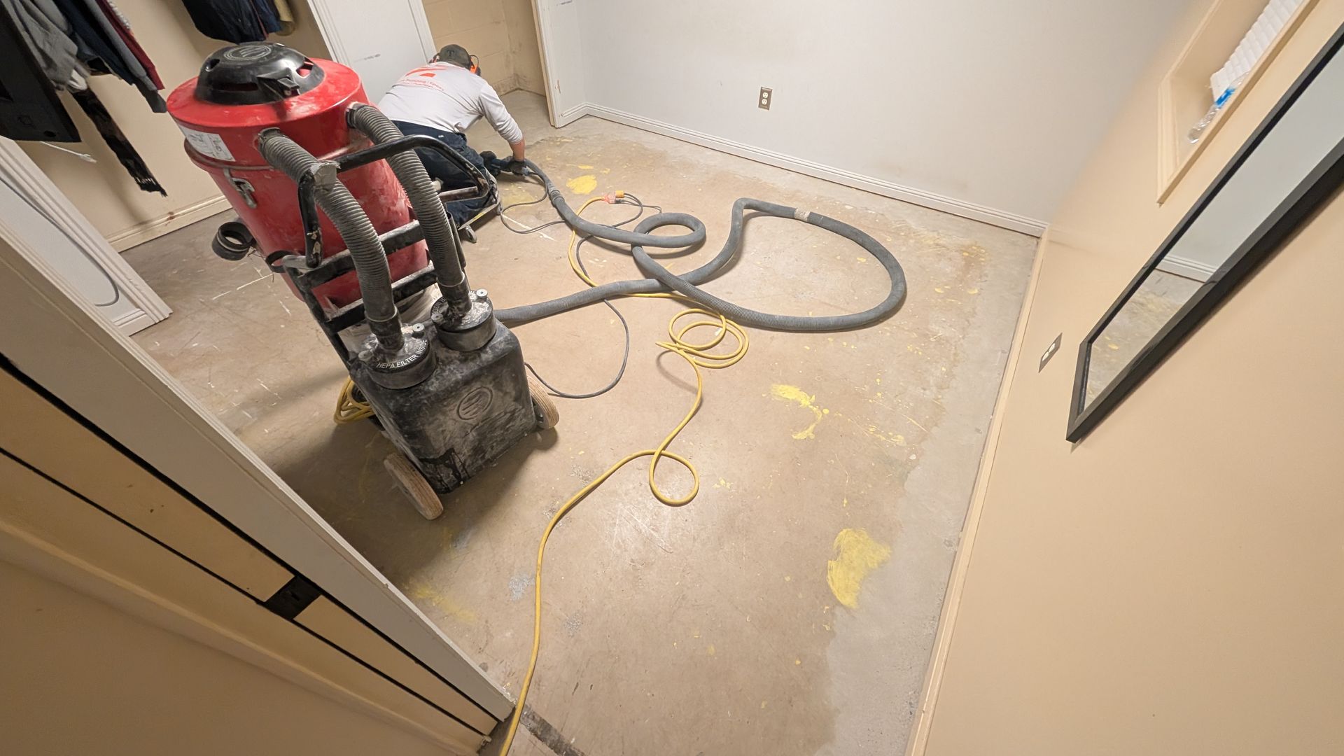 A man is using a vacuum cleaner to clean the floor of a room.