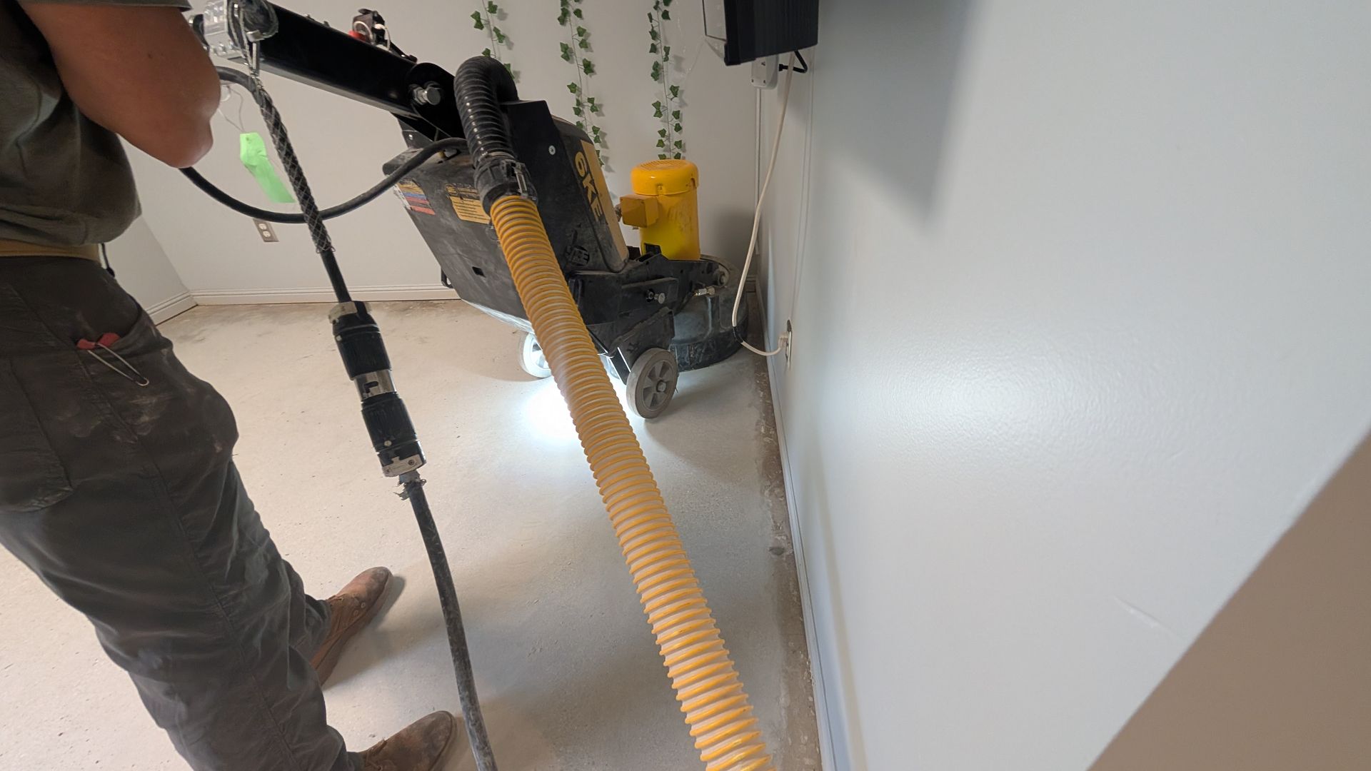 A man is using a vacuum cleaner to clean a wall.