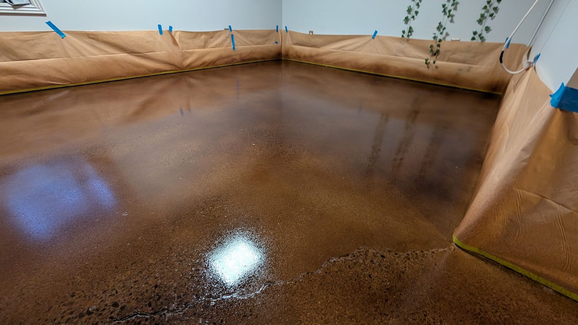 A room with a concrete floor that is being painted.