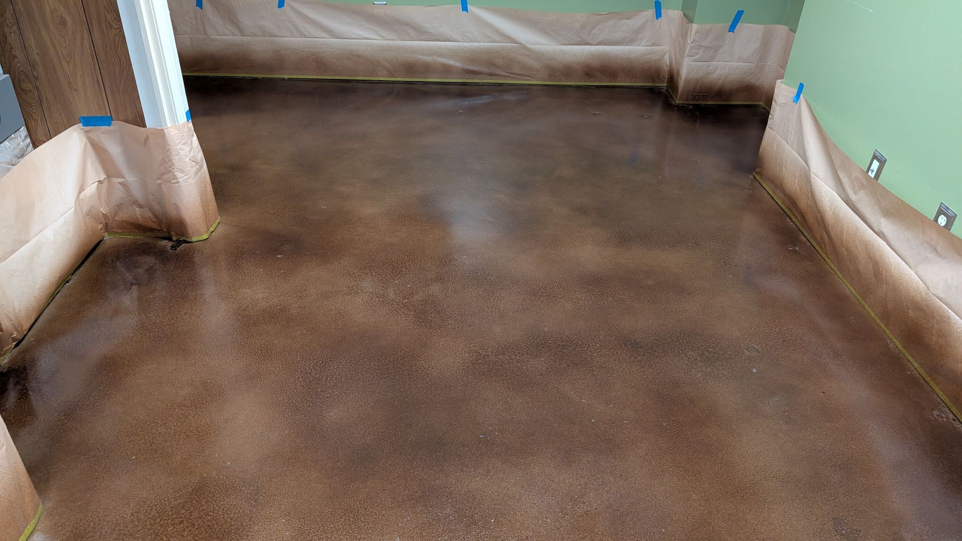 A concrete floor is being painted in a room.
