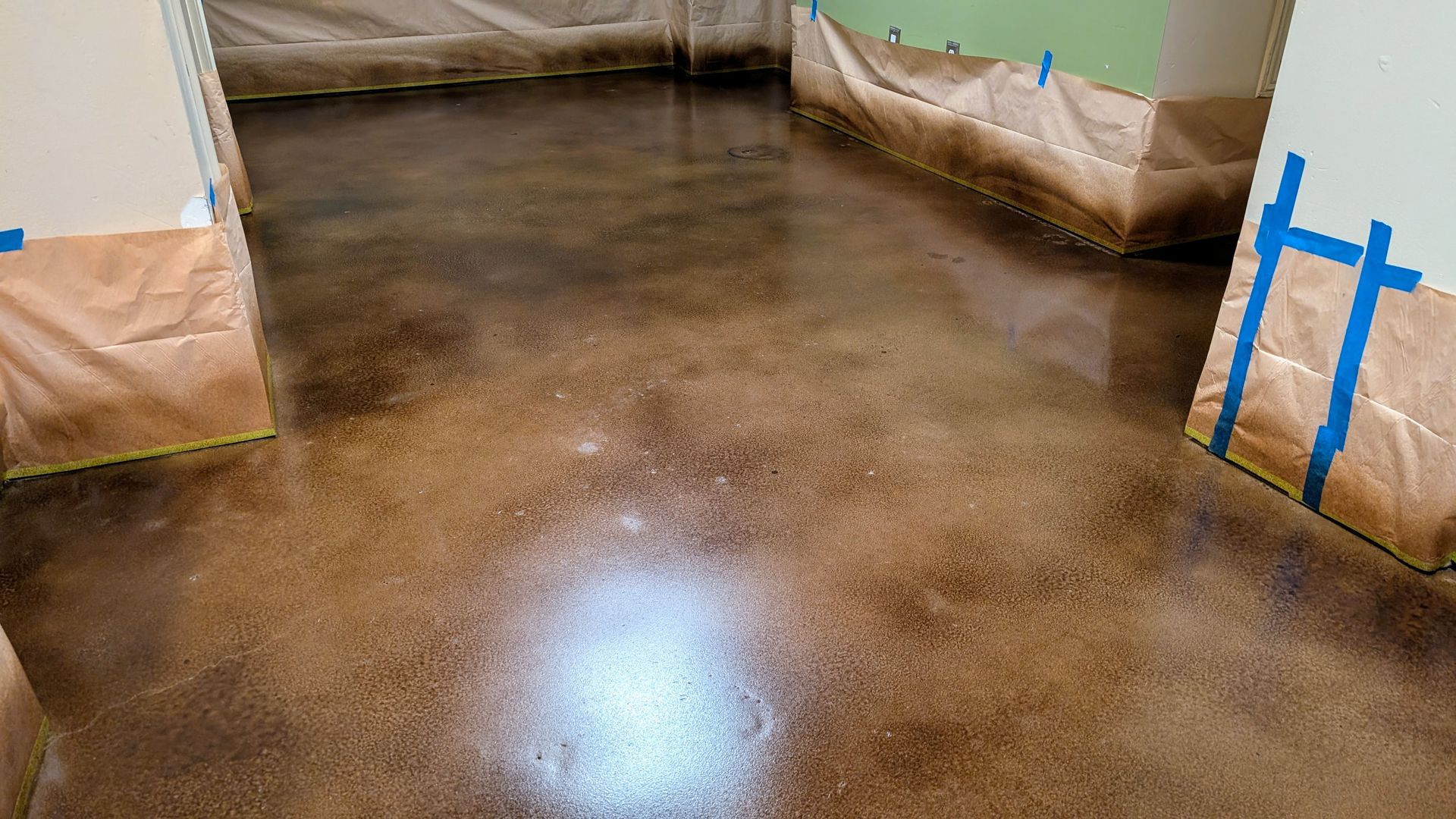 A concrete floor is being painted in a room.