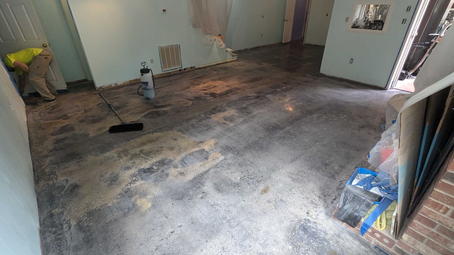 A person is cleaning the floor of a room with a broom.