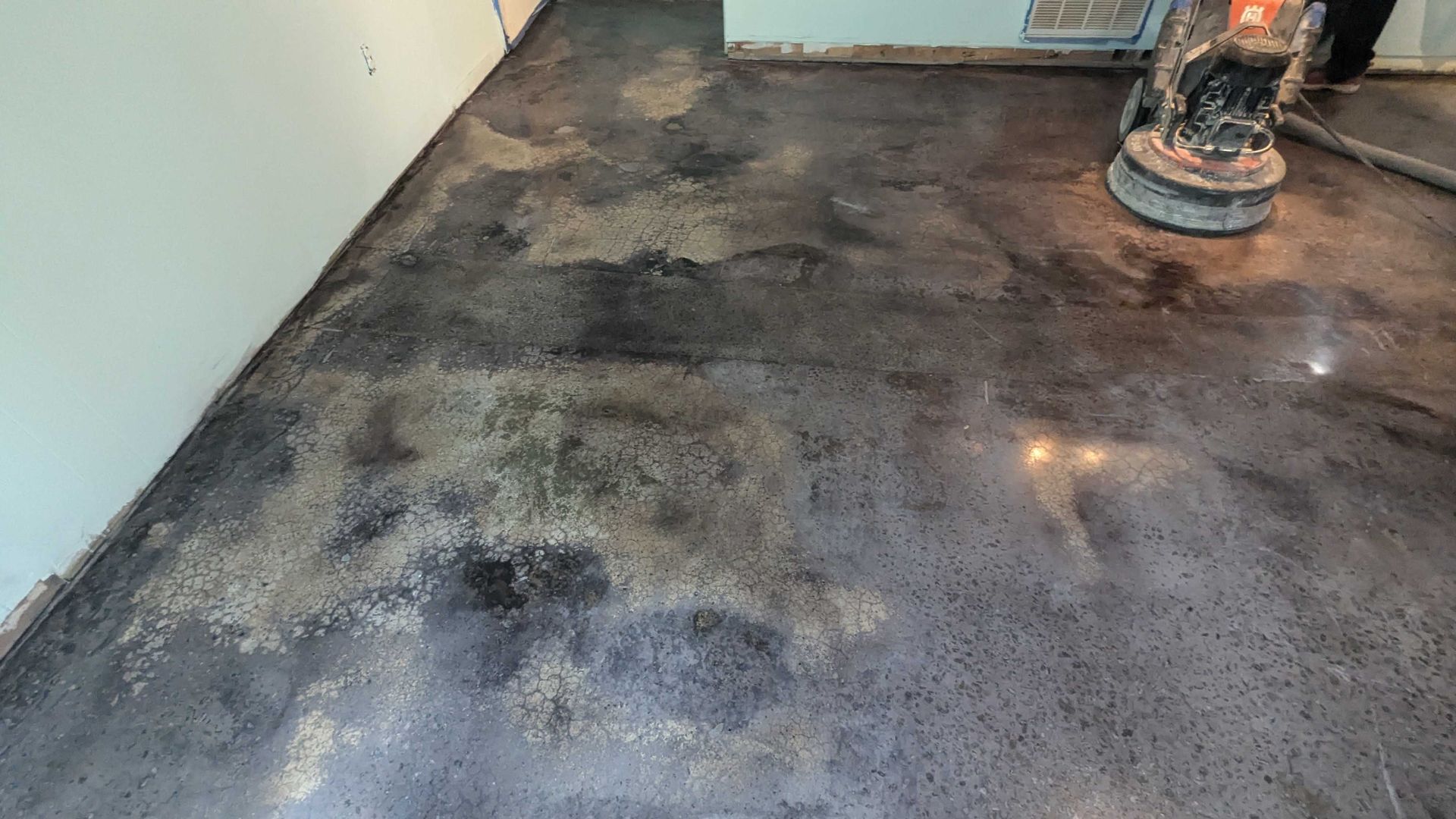 A person is polishing a concrete floor with a machine.