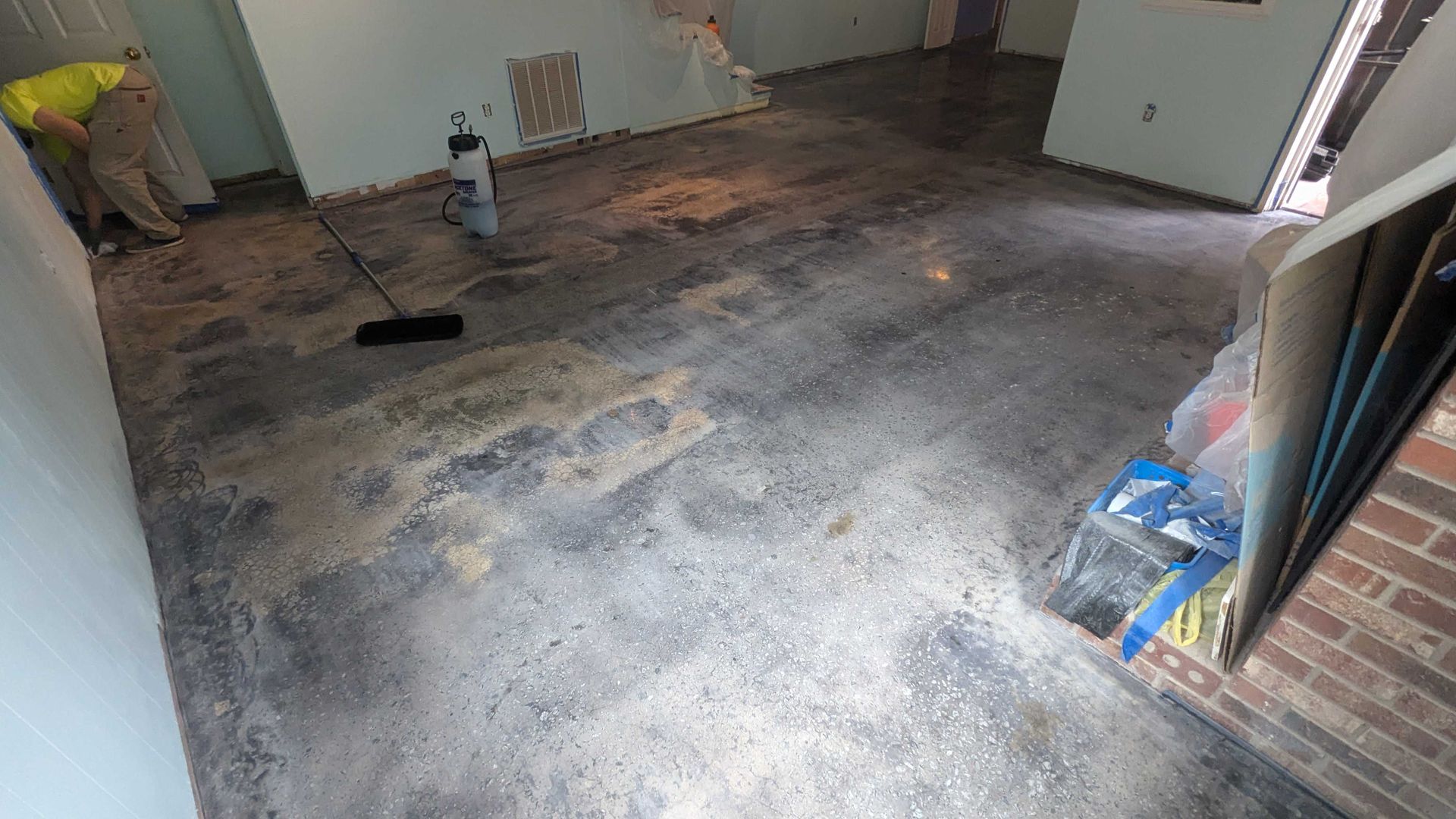 A man is cleaning the floor of a room with a broom.