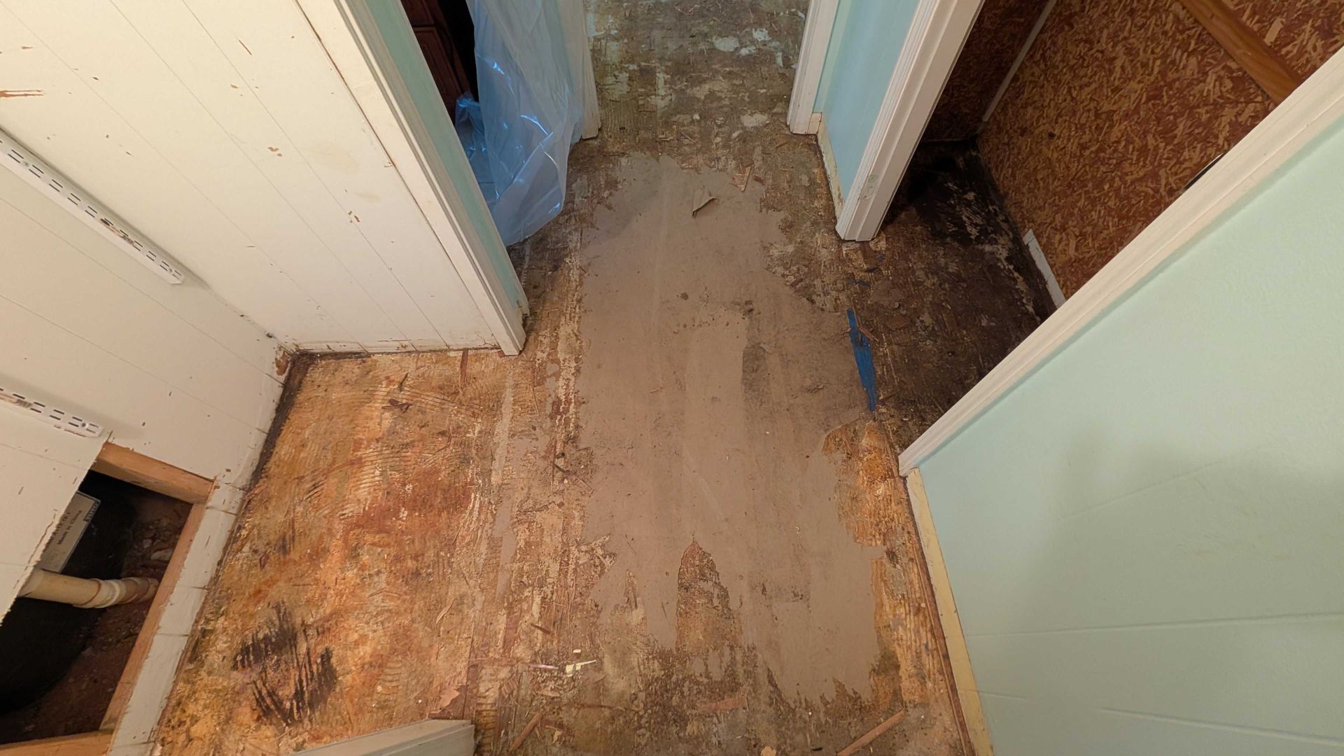 A hallway with a dirty floor and a few doors.