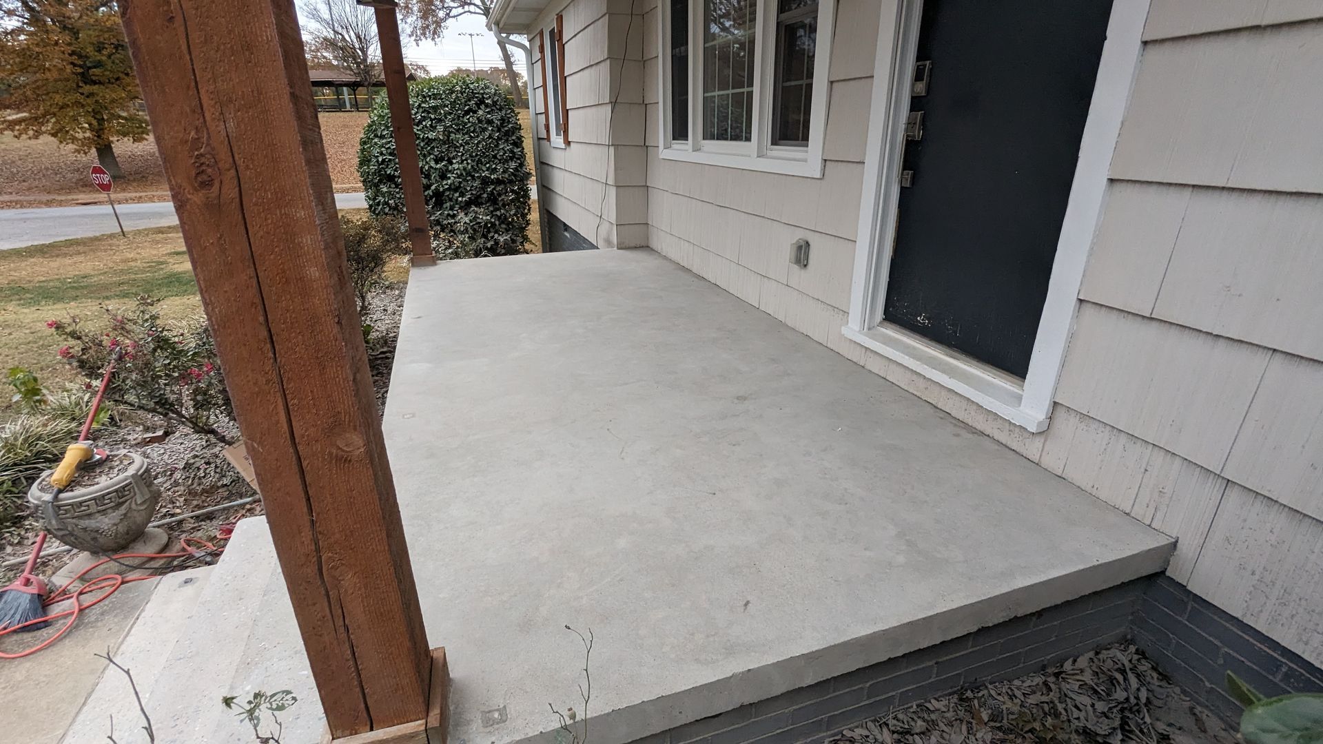 A concrete porch with a wooden post in front of a house.