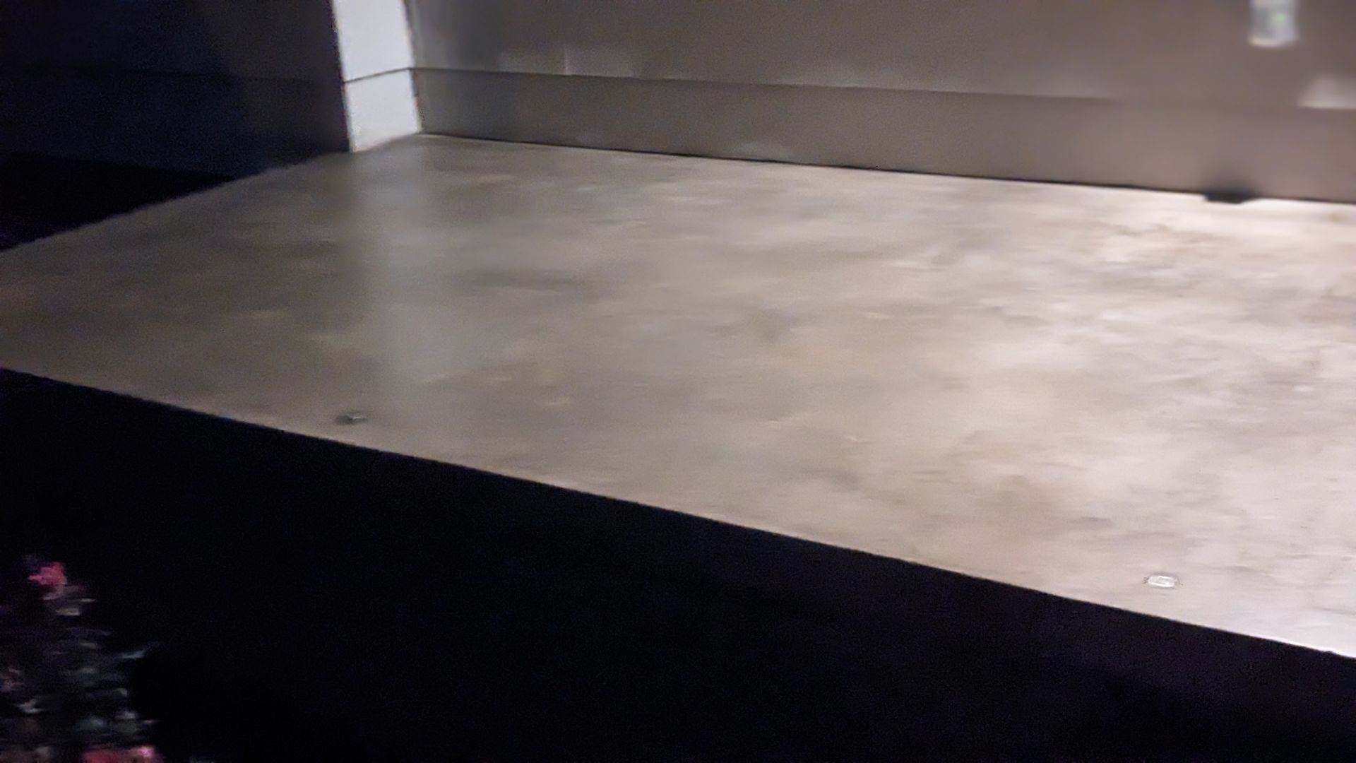 A concrete floor with a black border is in a dark room.