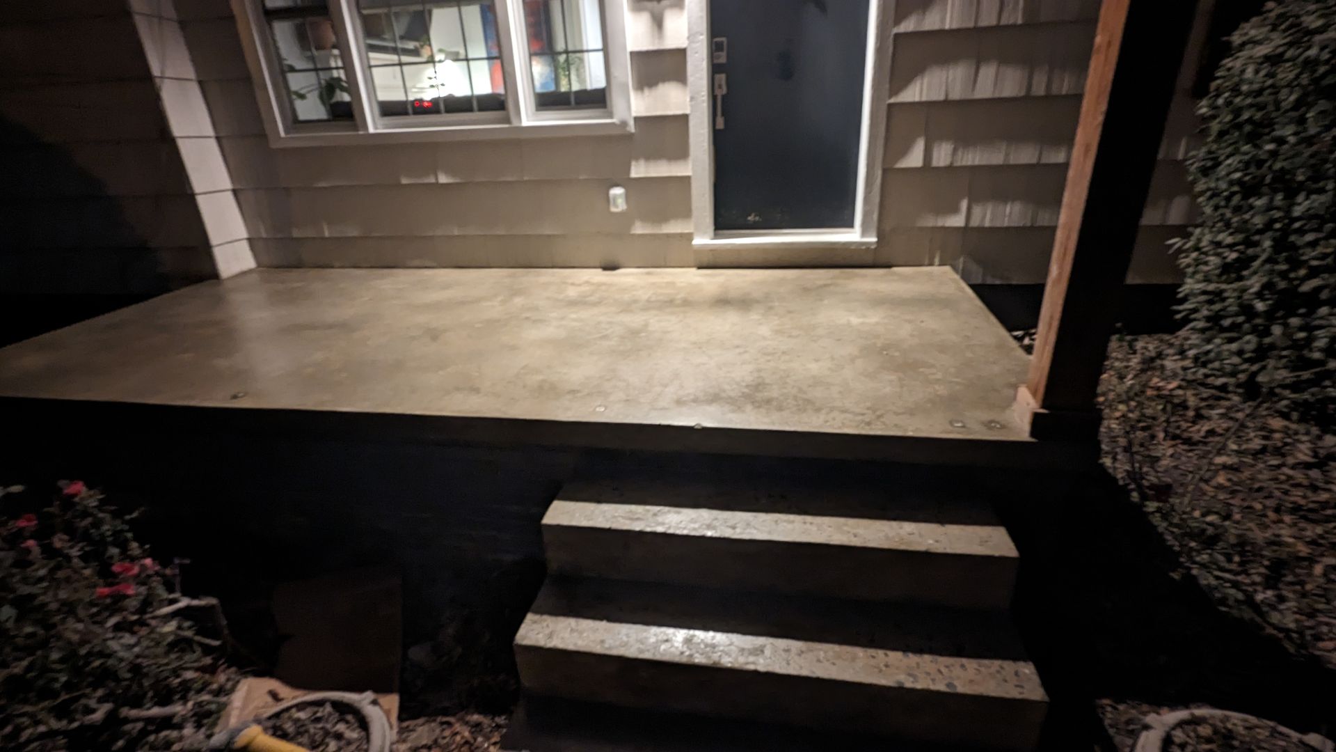 A concrete porch with stairs and a window in front of a house.