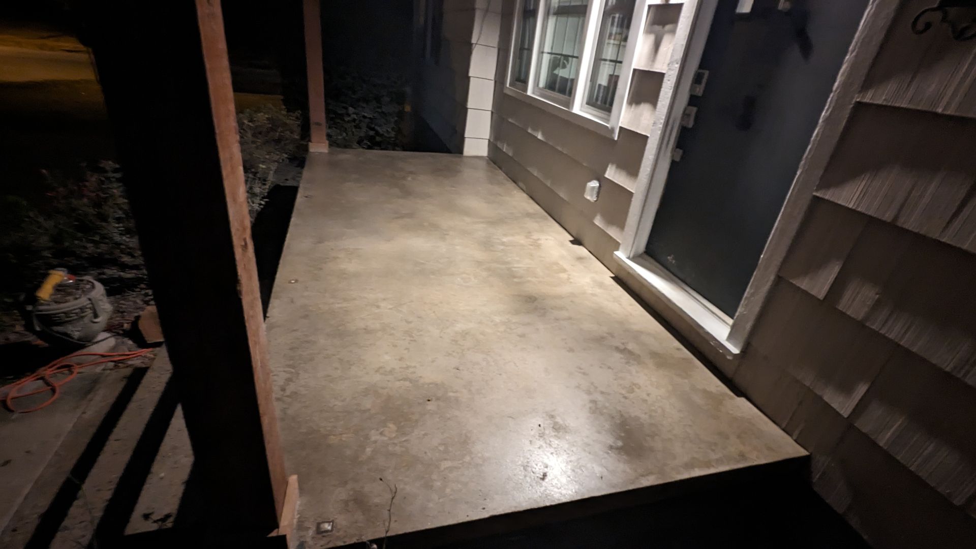 A concrete porch with a staircase leading up to it and a window.