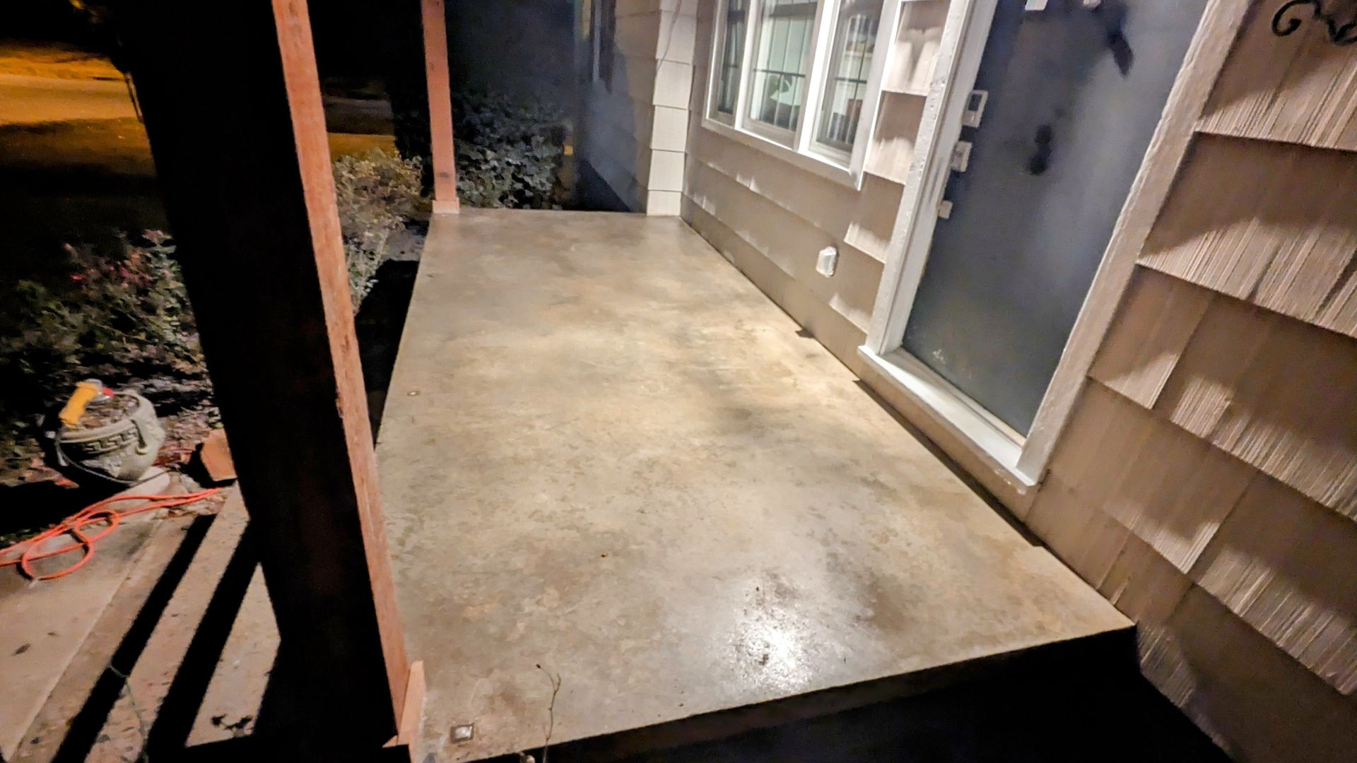 A porch with a concrete floor next to a house.
