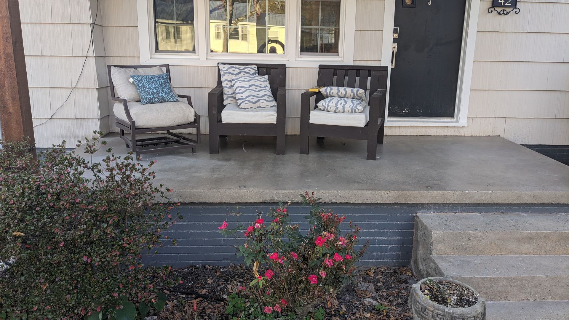 There are two chairs on the porch of a house.