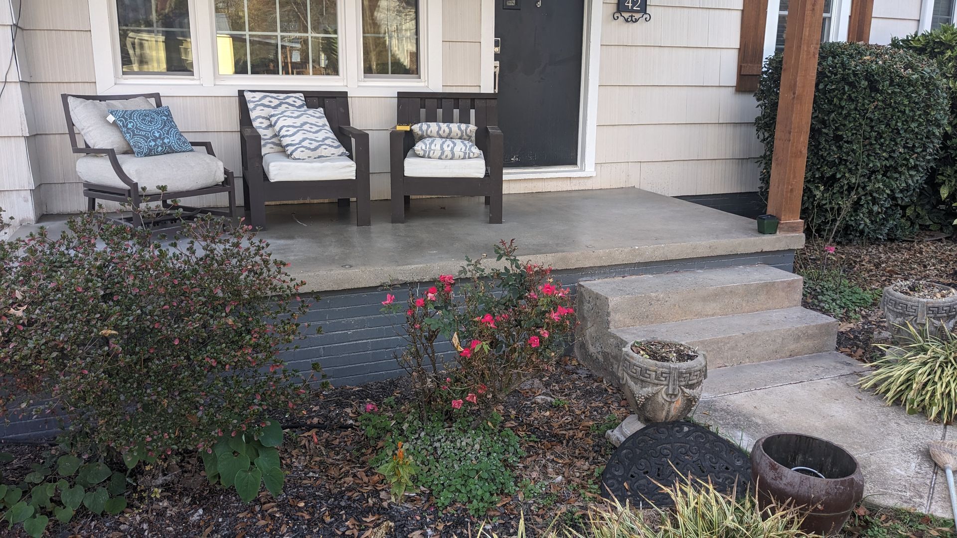There are two chairs on the porch of a house.