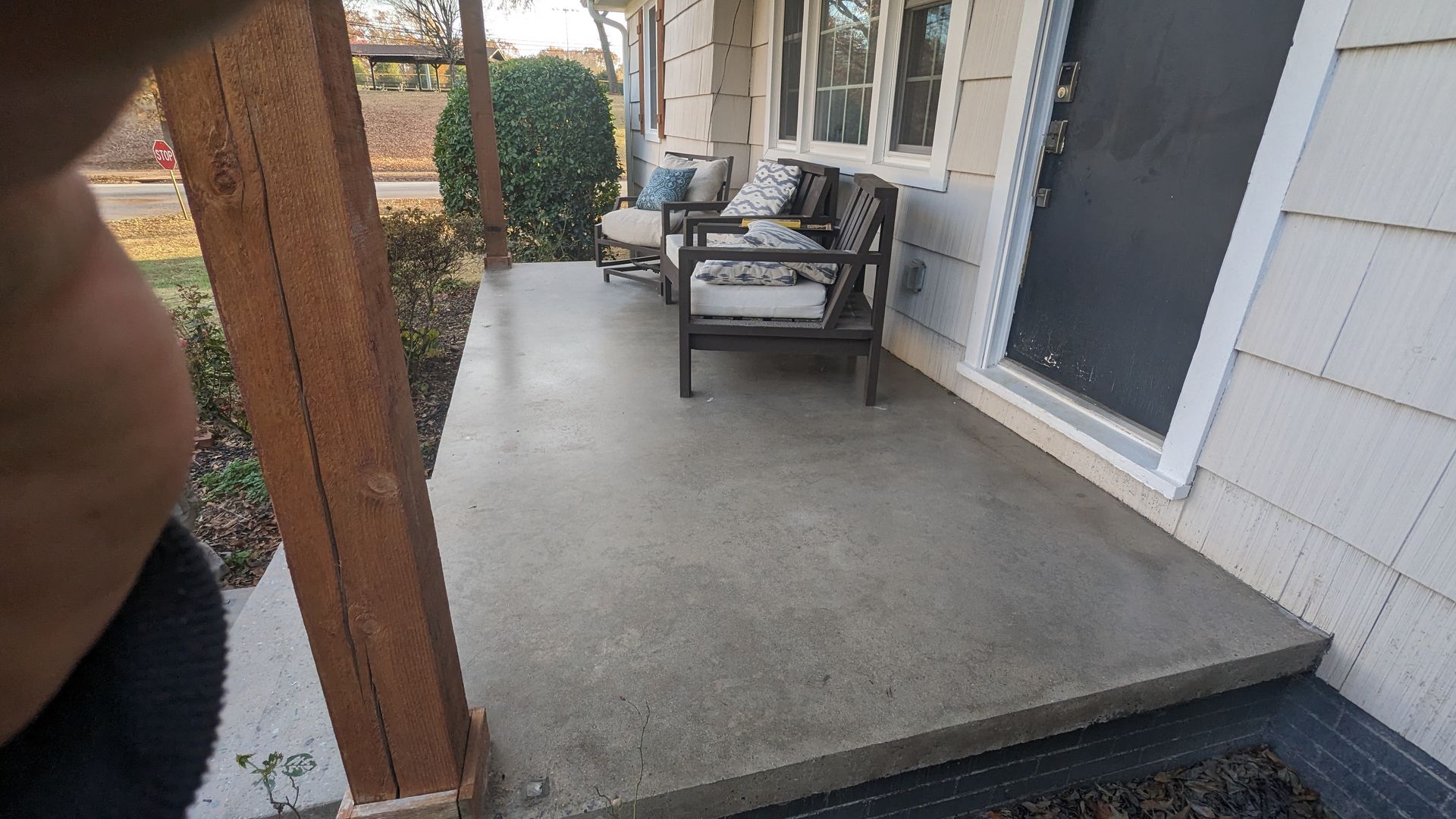 A concrete porch with a couch and chairs on it.