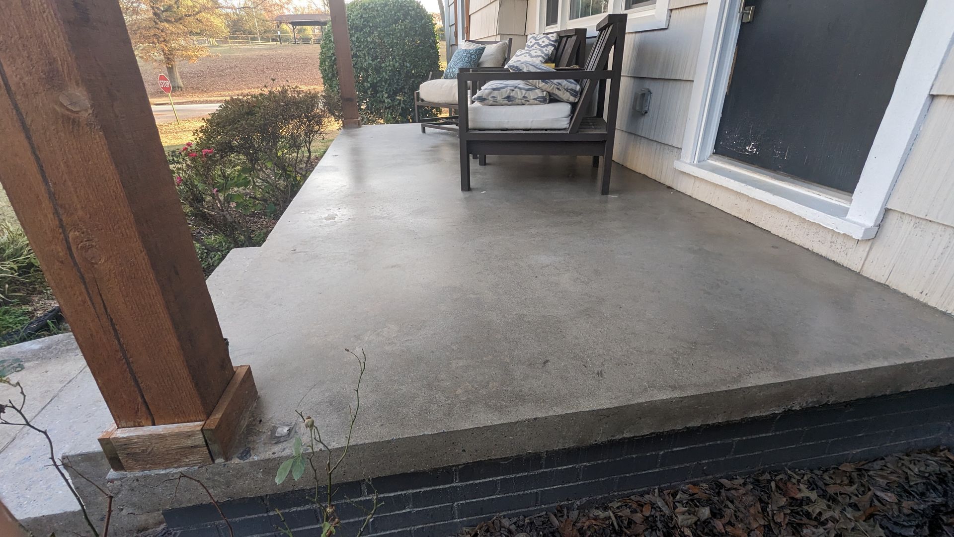 A concrete porch with a couch and chairs on it.