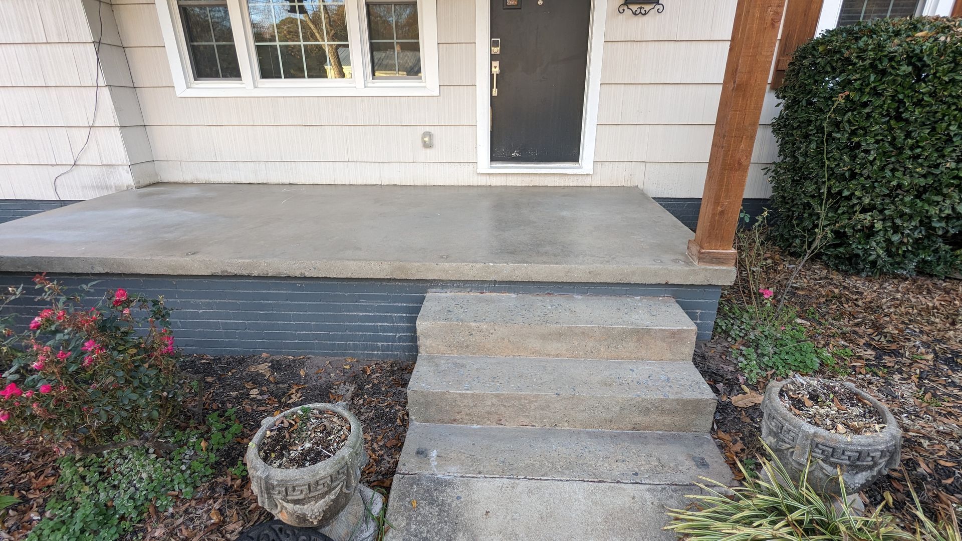 A concrete porch with steps leading to the front door of a house.