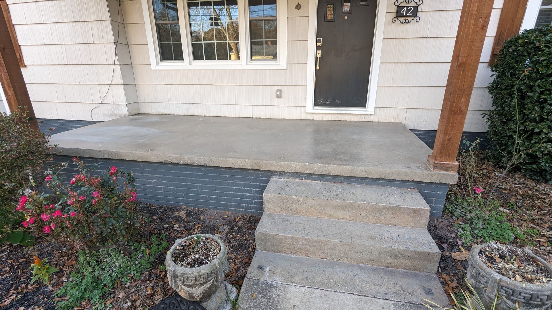 A concrete porch with steps leading to the front door of a house.