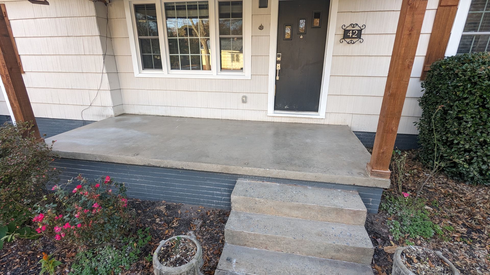 A concrete porch with stairs leading to the front door of a house.
