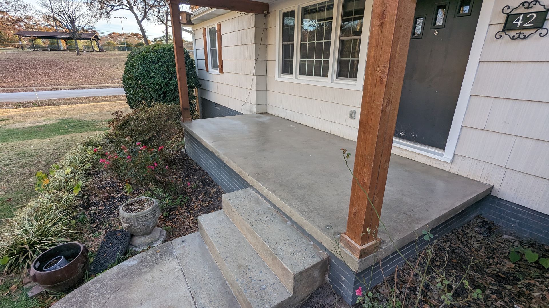 A concrete porch with stairs leading up to it and a house in the background.