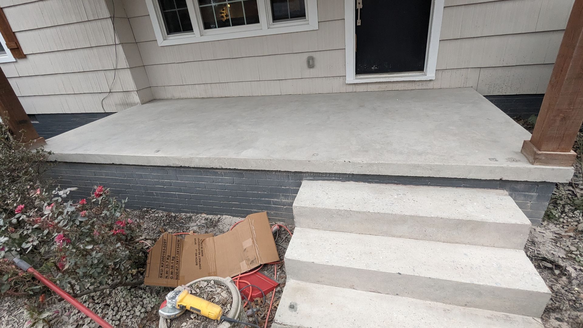 A concrete porch with stairs leading up to the front door of a house.