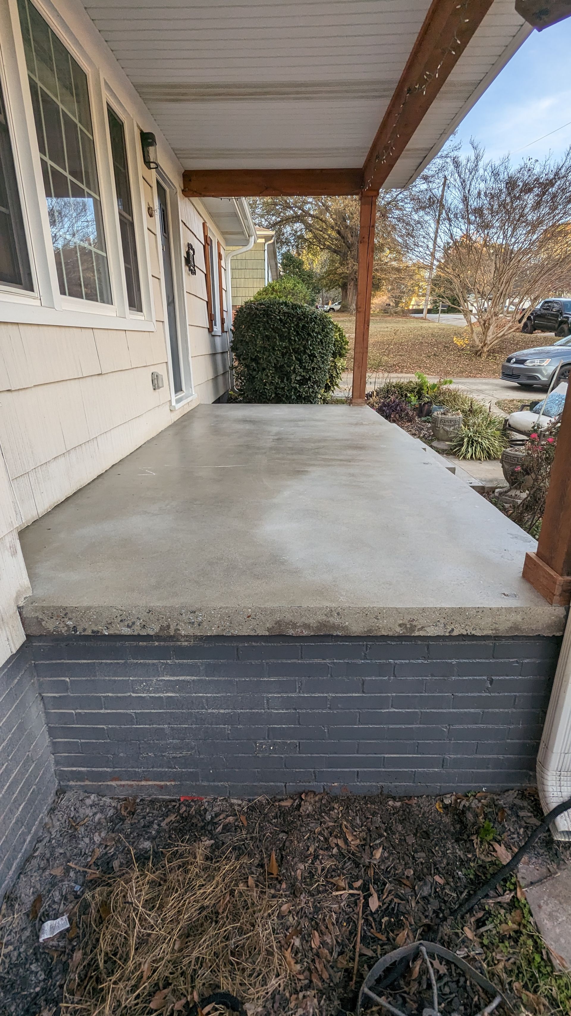 A porch with a concrete floor and steps on a house.