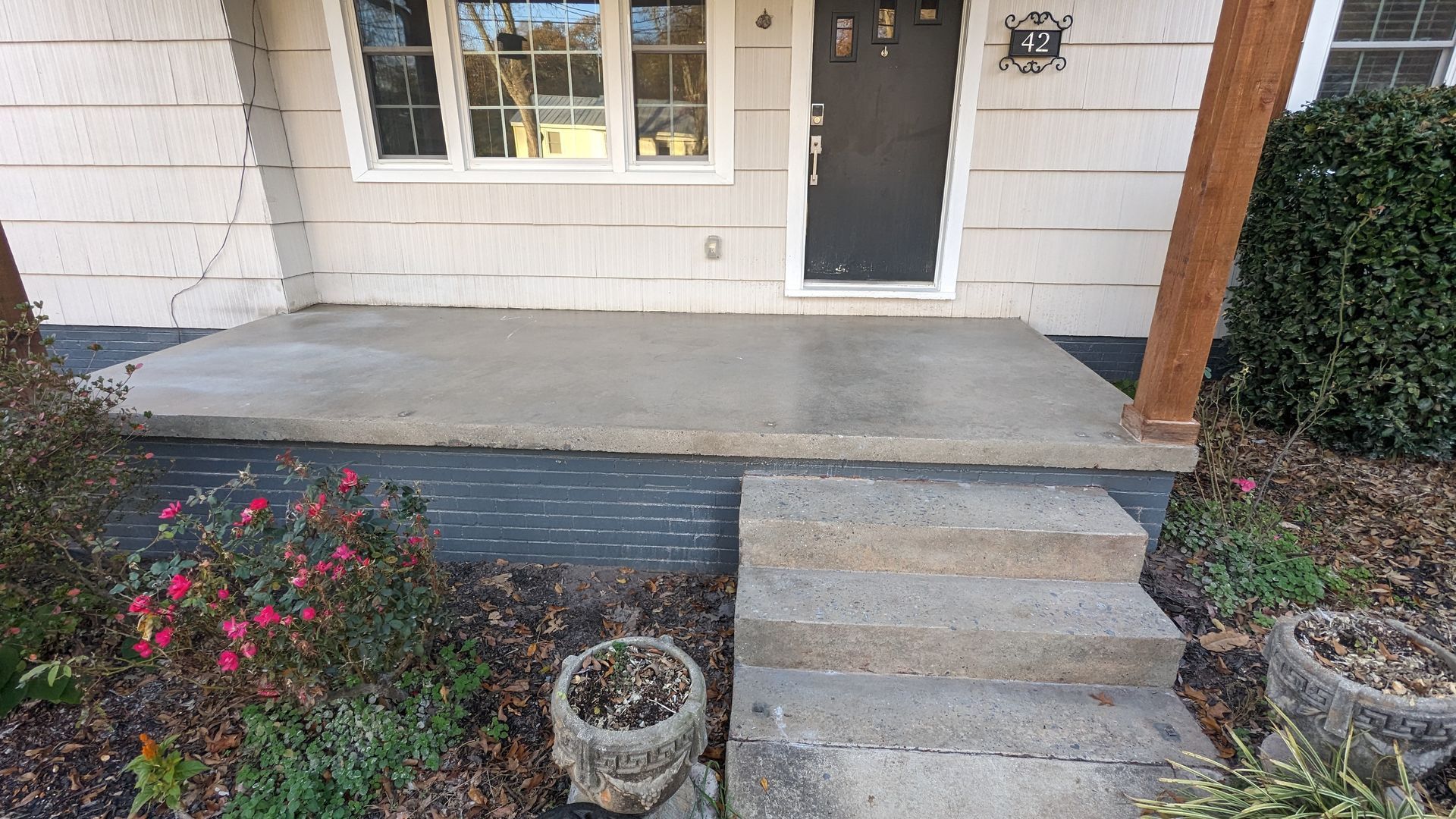 A concrete porch with steps leading to the front door of a house.