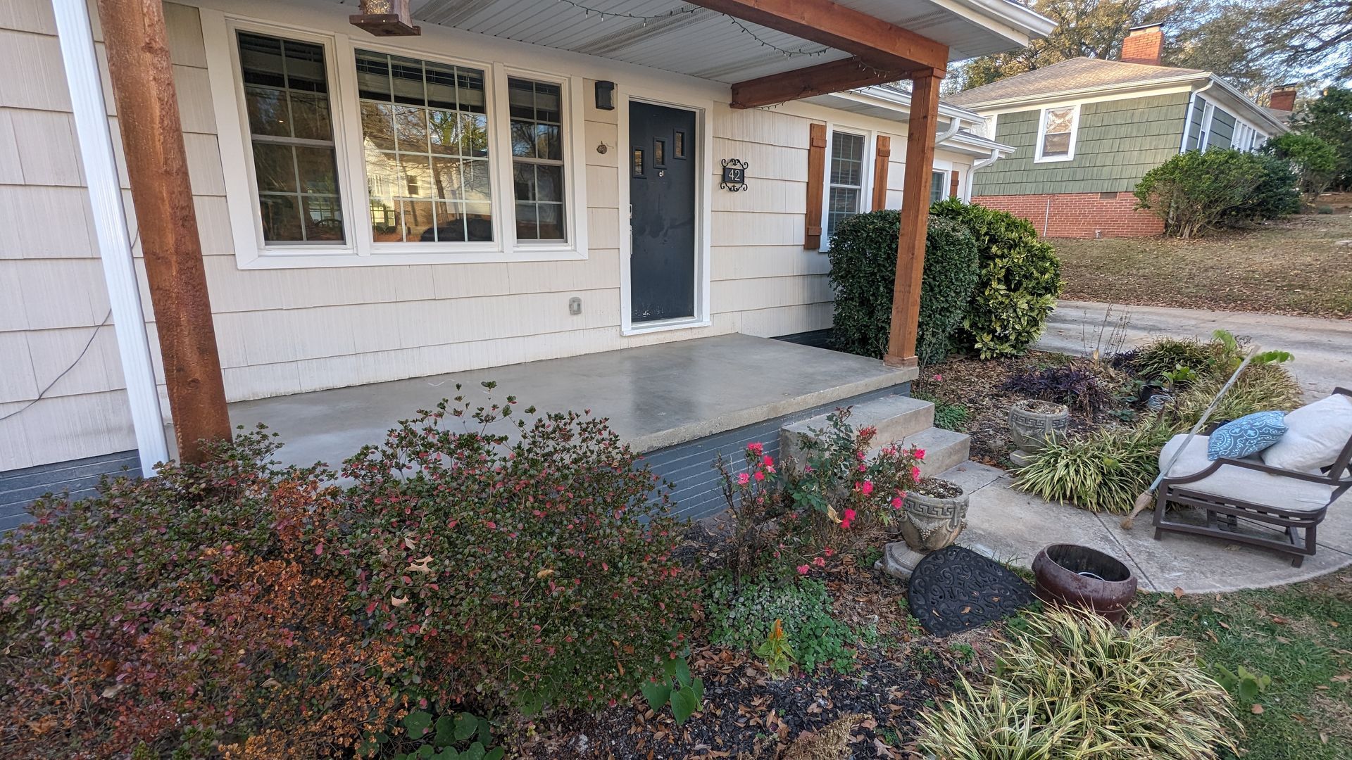 A house with a porch and a garden in front of it.