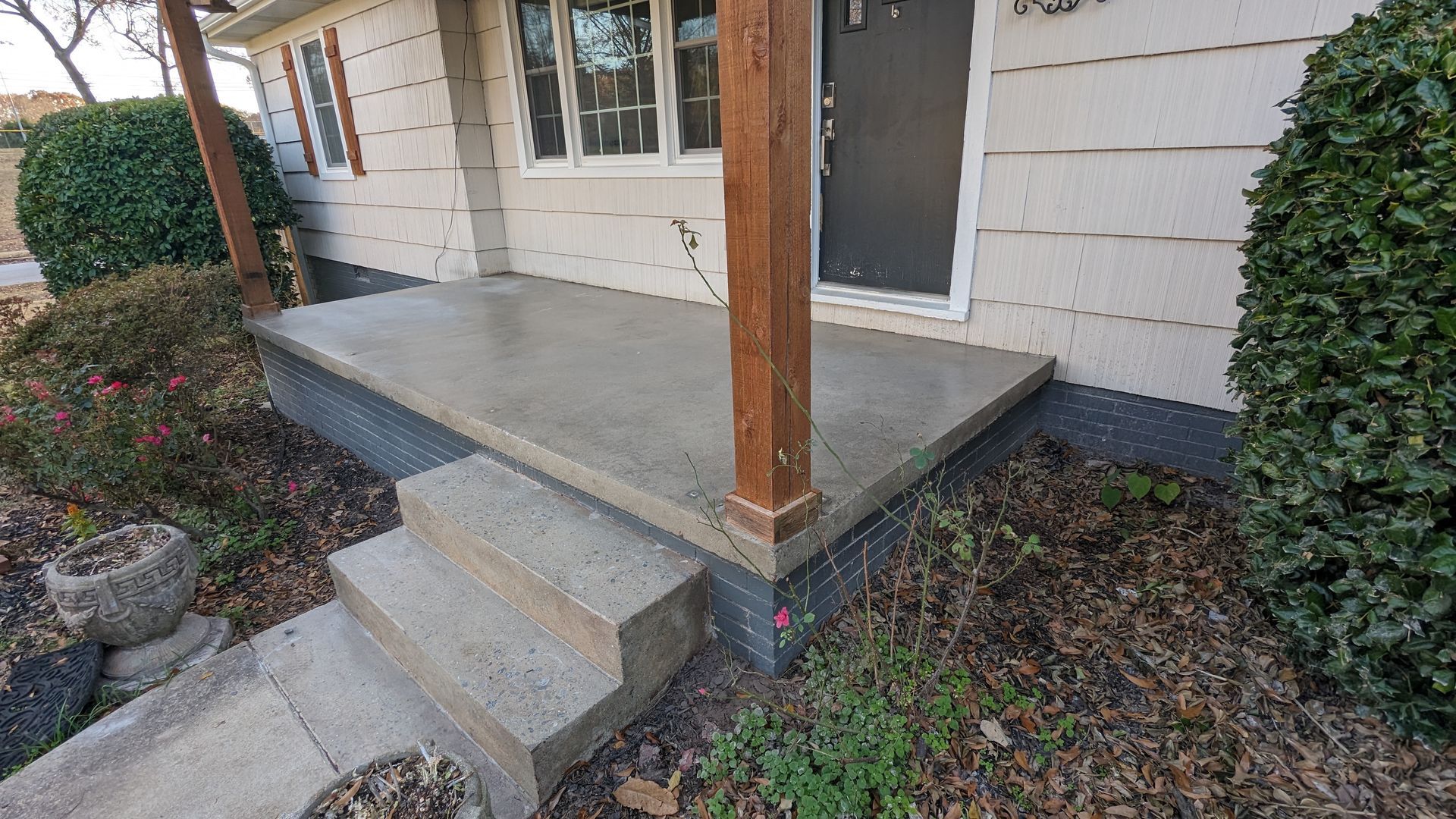 A concrete porch with stairs leading up to it is in front of a house.