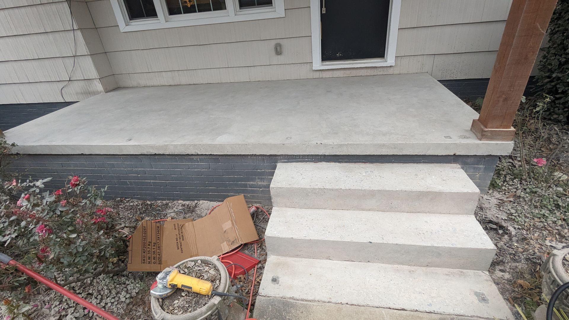 A concrete porch with stairs leading up to the front door of a house.