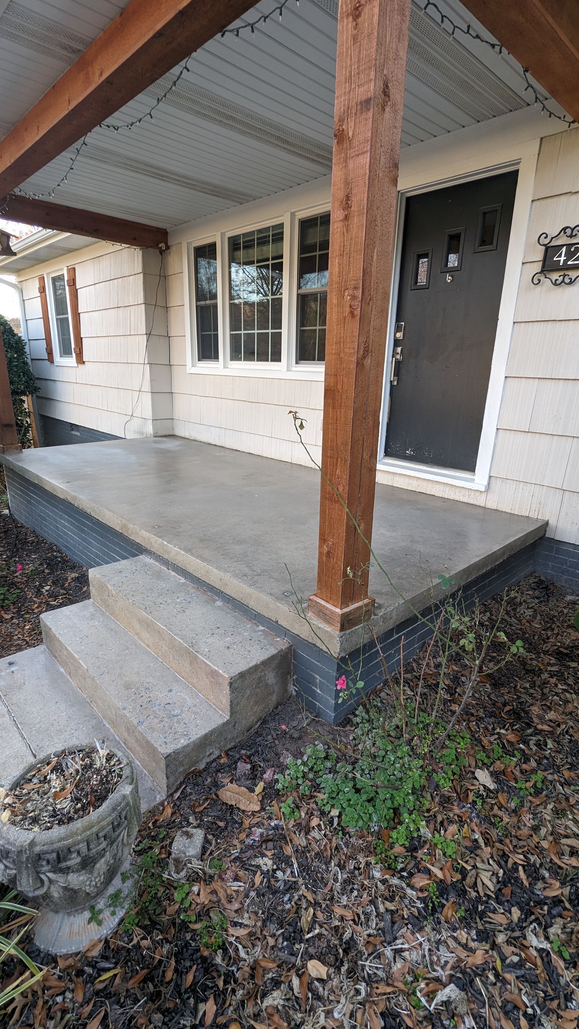 A concrete porch with stairs leading to the front door of a house.