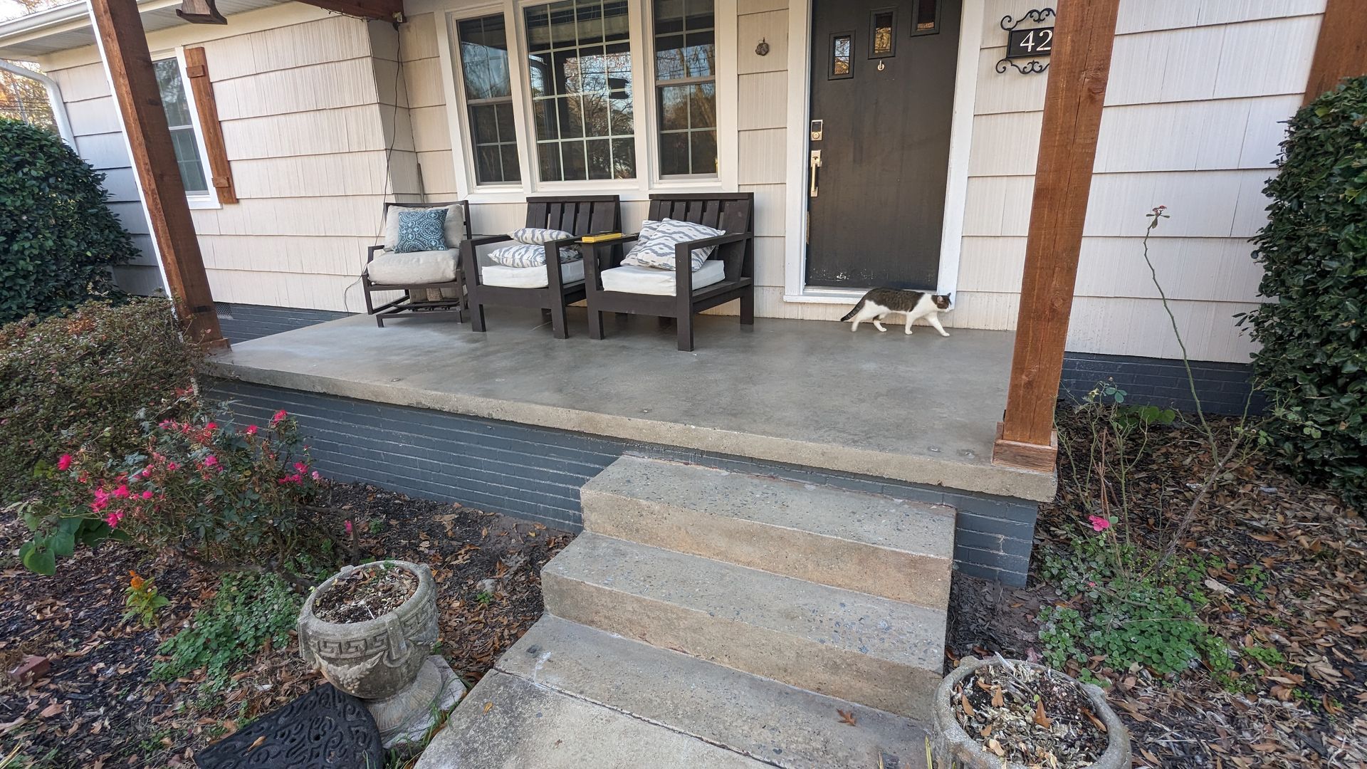 There is a porch with chairs and a dog on it.