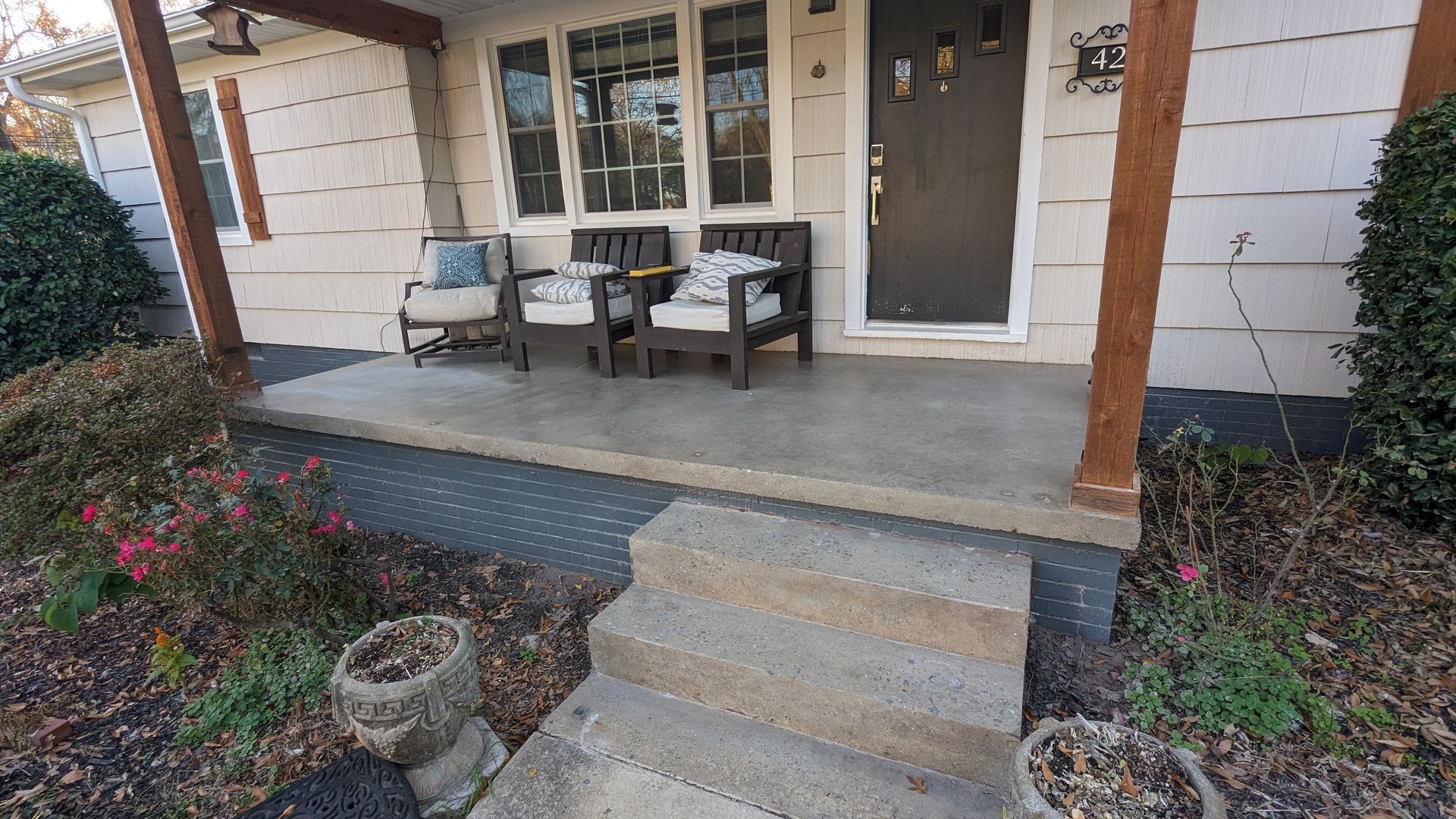 A white house with a porch with chairs and stairs leading to it.