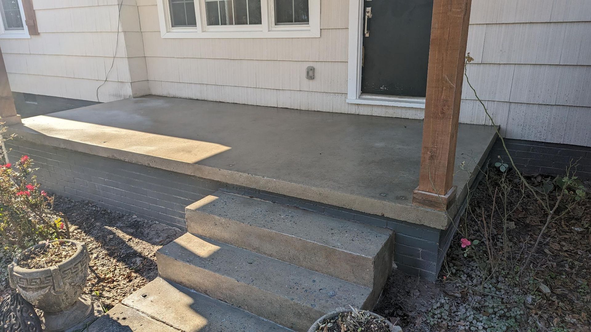 A concrete porch is being built in front of a house.