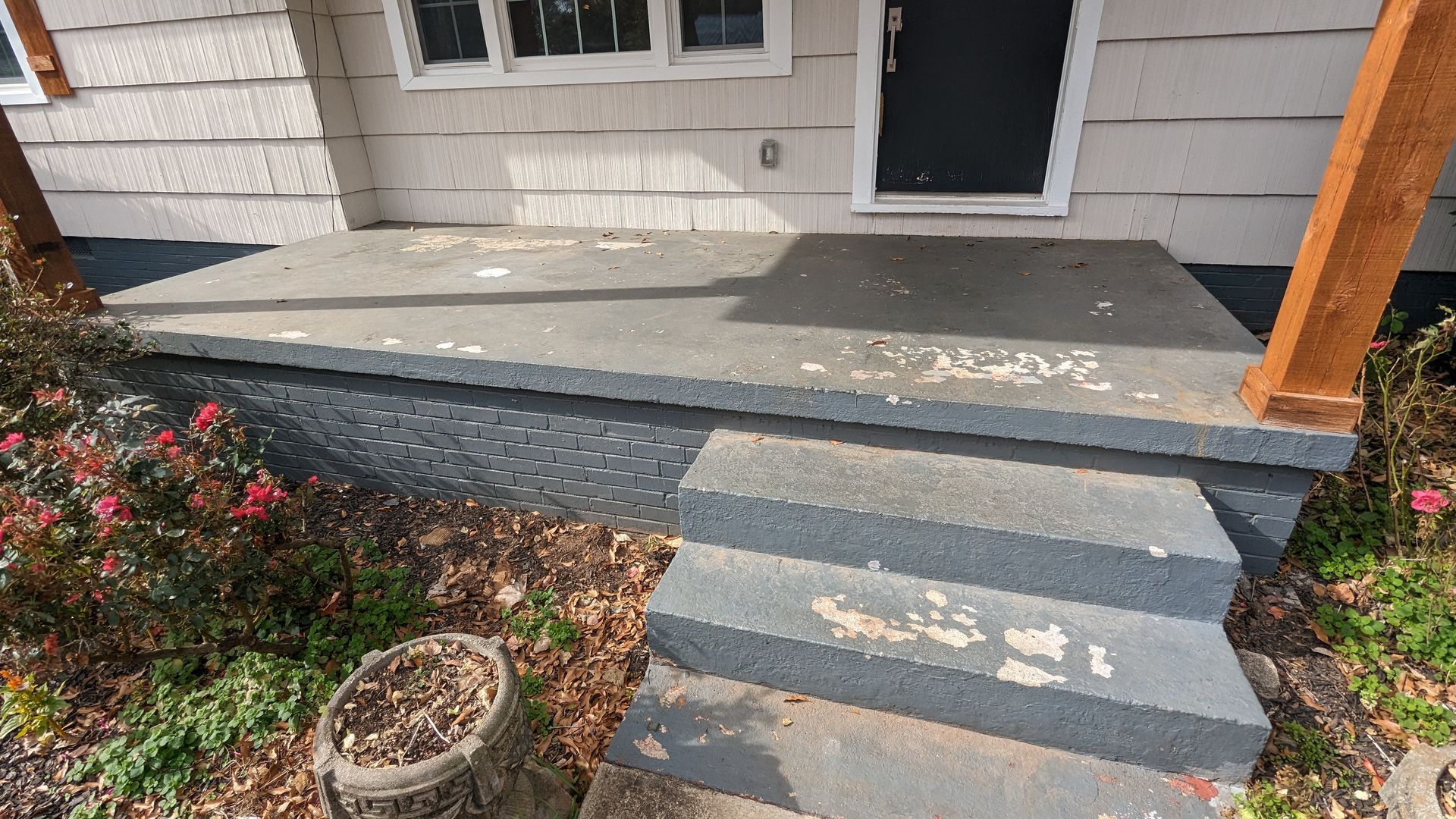 A porch with stairs leading up to the front door of a house.