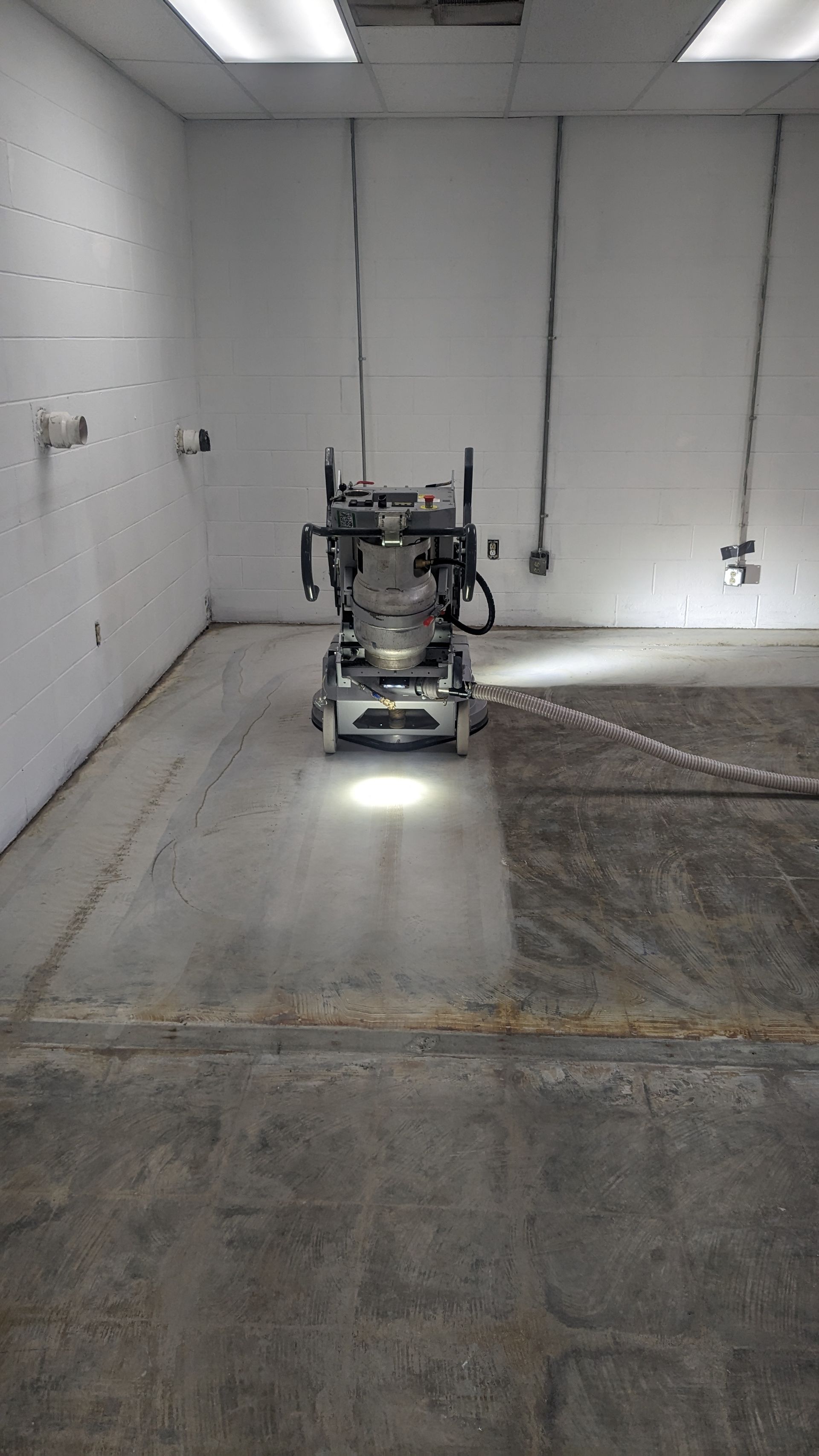 A machine is grinding a concrete floor in a room.