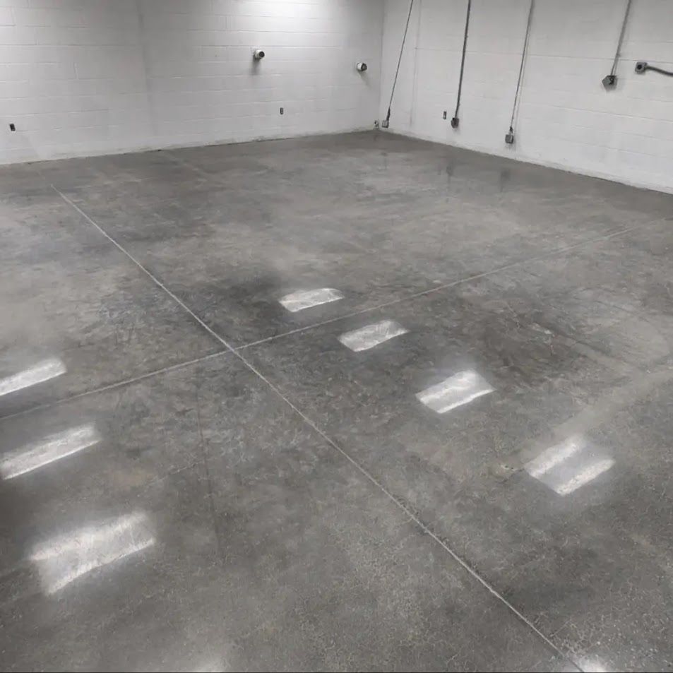A large empty room with a concrete floor and white walls.