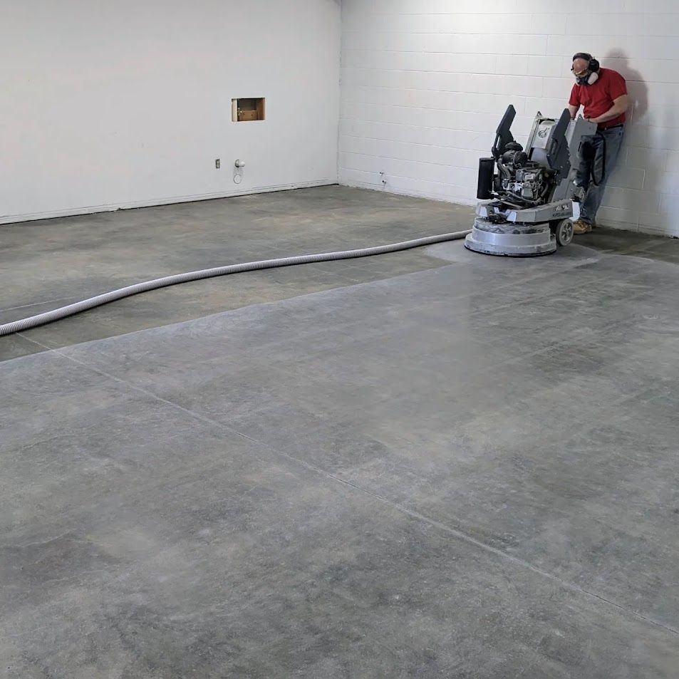 A man is standing next to a machine on a concrete floor.