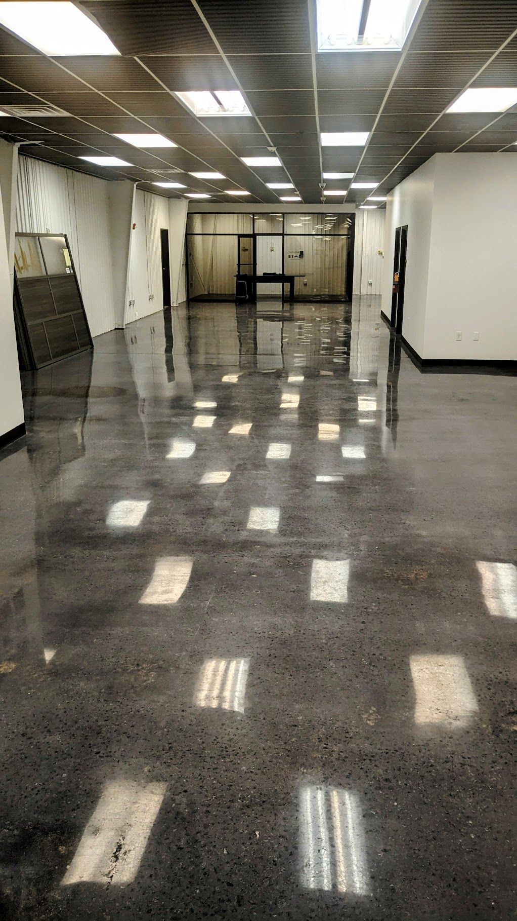 A large empty room with a shiny floor and ceiling lights.