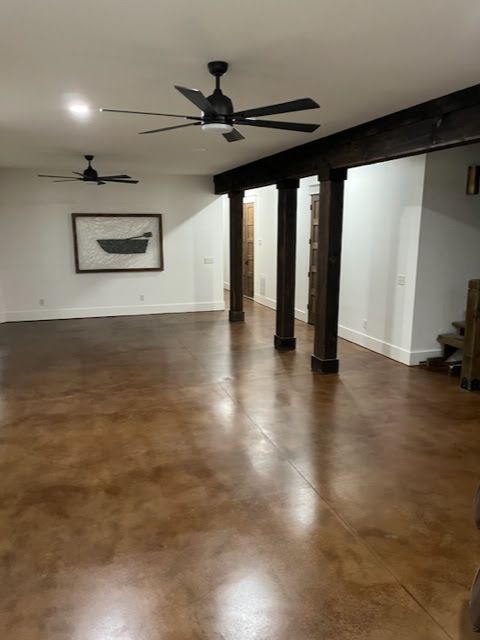 Large room with brown polished concrete floor, dark wood beams, and ceiling fans.